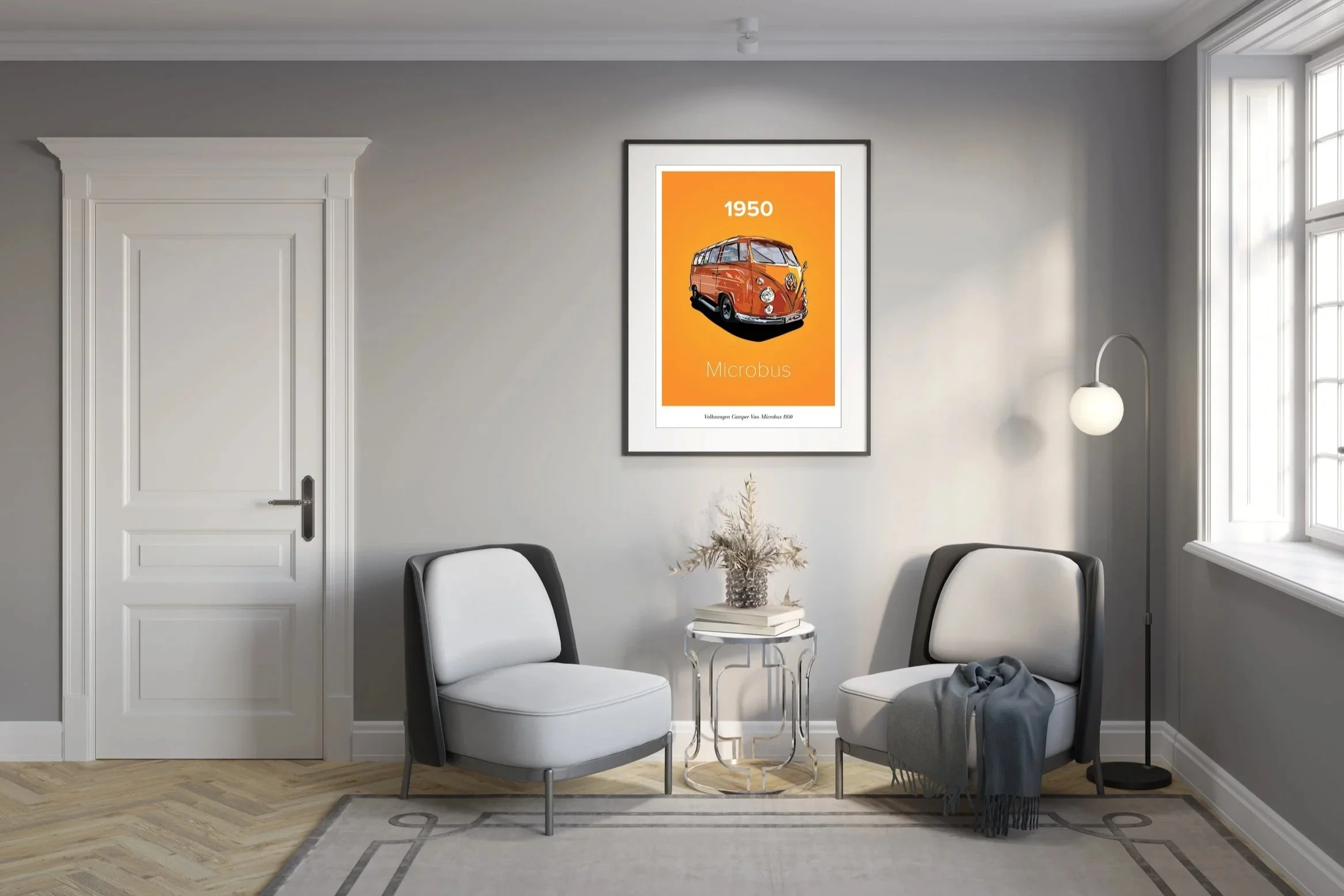 Living room with gray walls, two white and black armchairs, a small glass side table with books and a plant, a standing lamp, a framed poster of a 1950 Volkswagen Microbus on the wall, and a window with white trim.