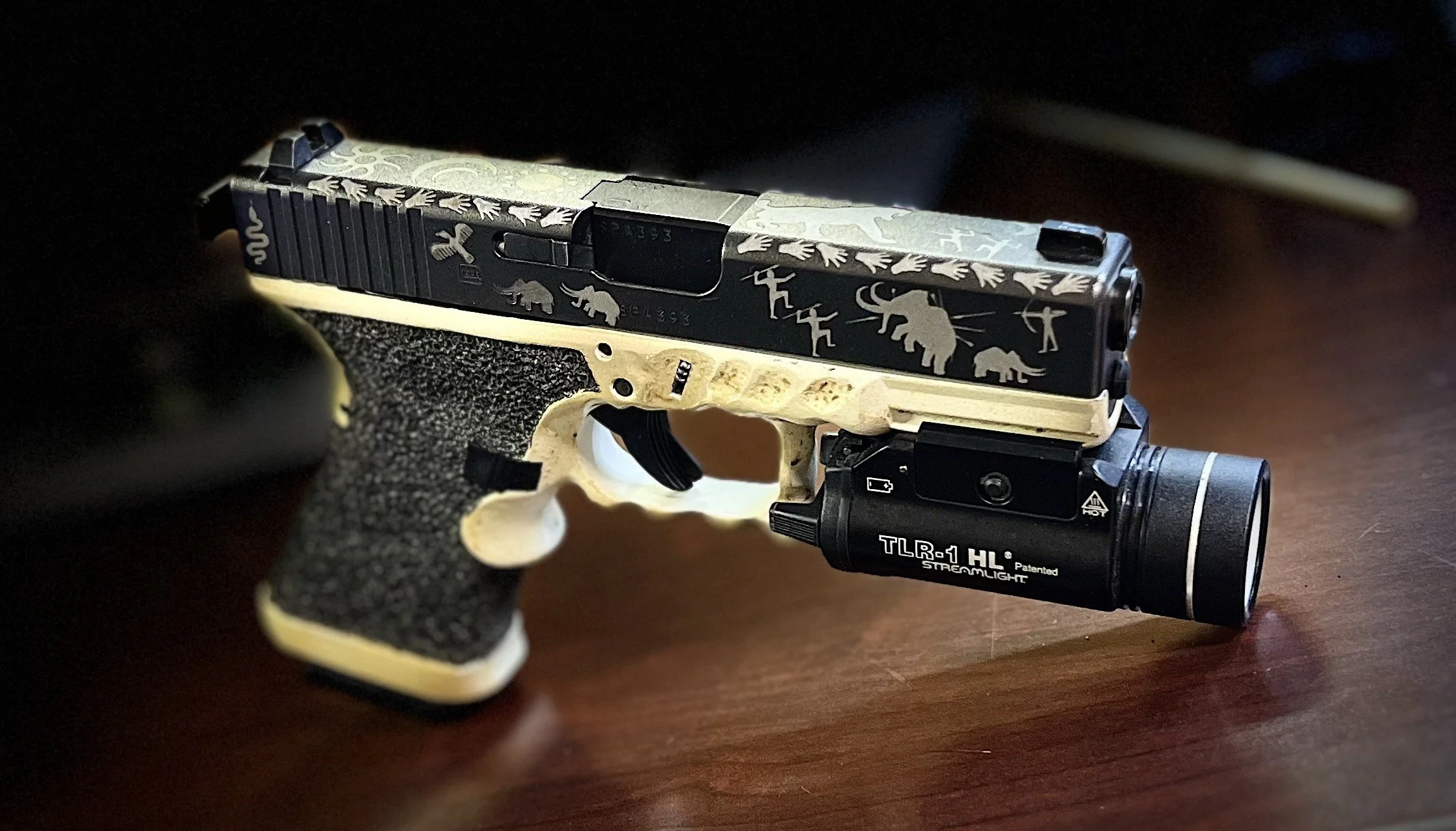 Custom Glock® 19 featuring decorative slide engraving, a two-tone Cerakoted frame, and hand-stippled grip, showcasing detailed craftsmanship and personalized design work.