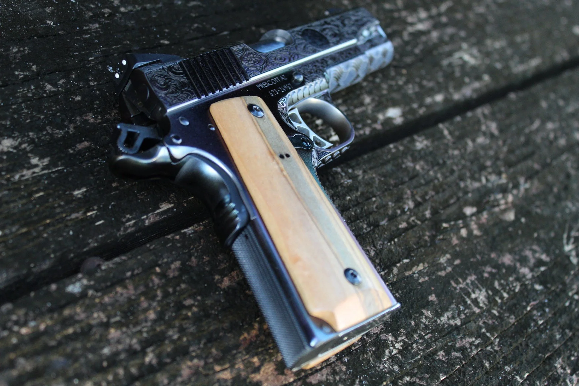 One-of-a-kind Ruger® 1911 featuring intricate scroll engraving, iridescent metal finish, and wood grip panels, custom designed and engraved for a client.