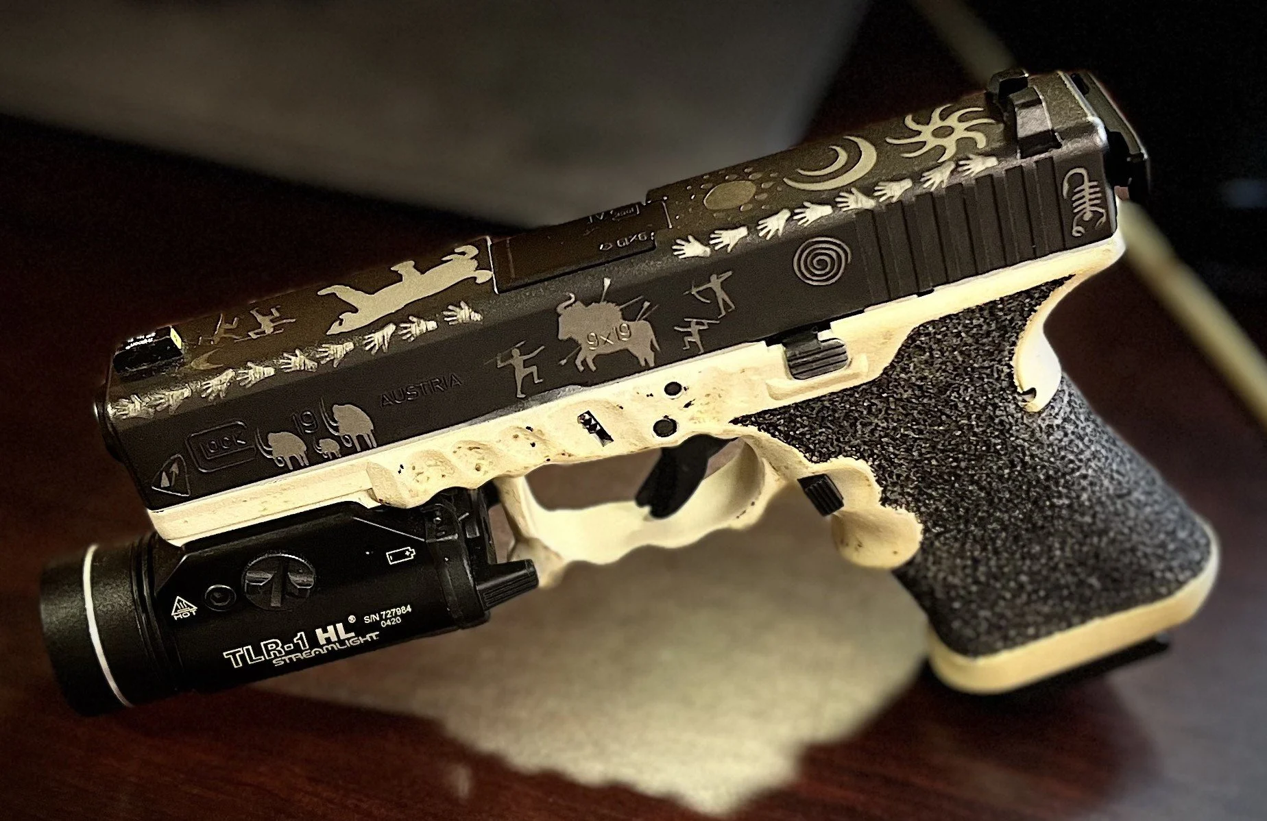 Custom Glock® 19 featuring decorative slide engraving, a two-tone Cerakoted frame, and hand-stippled grip, showcasing detailed craftsmanship and personalized design work.