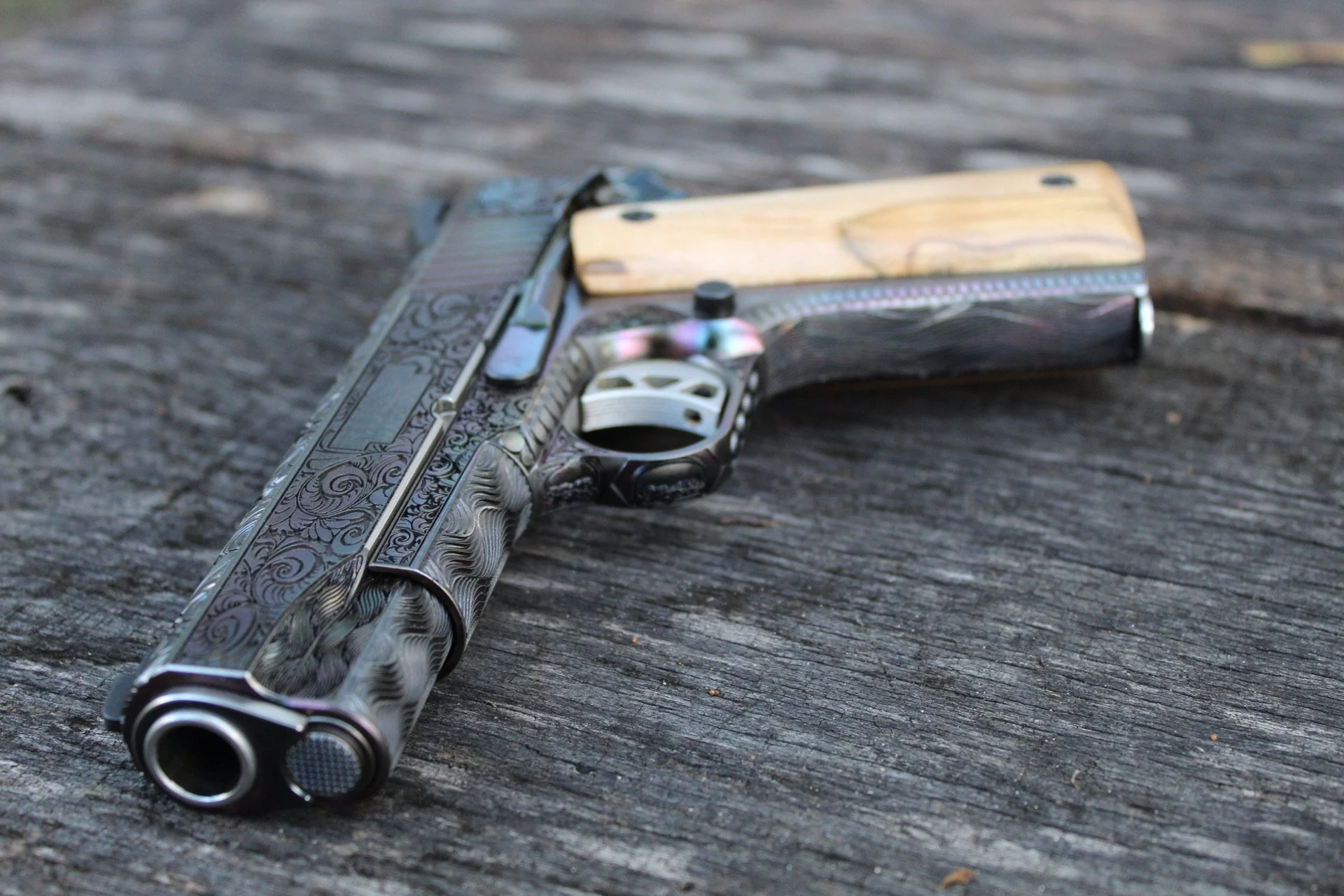 One-of-a-kind Ruger® 1911 featuring intricate scroll engraving, iridescent metal finish, and wood grip panels, custom designed and engraved for a client.