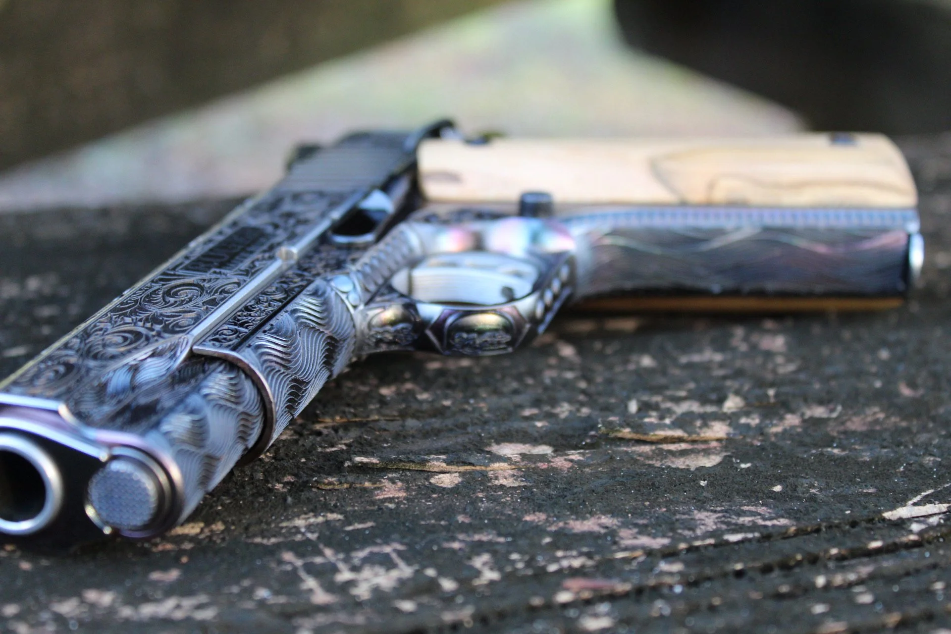 One-of-a-kind Ruger® 1911 featuring intricate scroll engraving, iridescent metal finish, and wood grip panels, custom designed and engraved for a client.