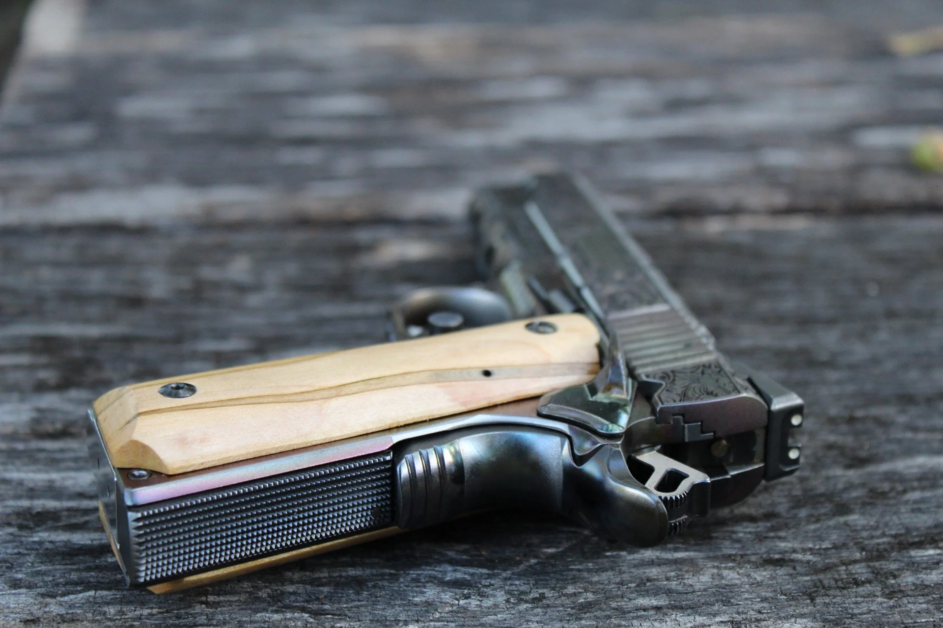 One-of-a-kind Ruger® 1911 featuring intricate scroll engraving, iridescent metal finish, and wood grip panels, custom designed and engraved for a client.