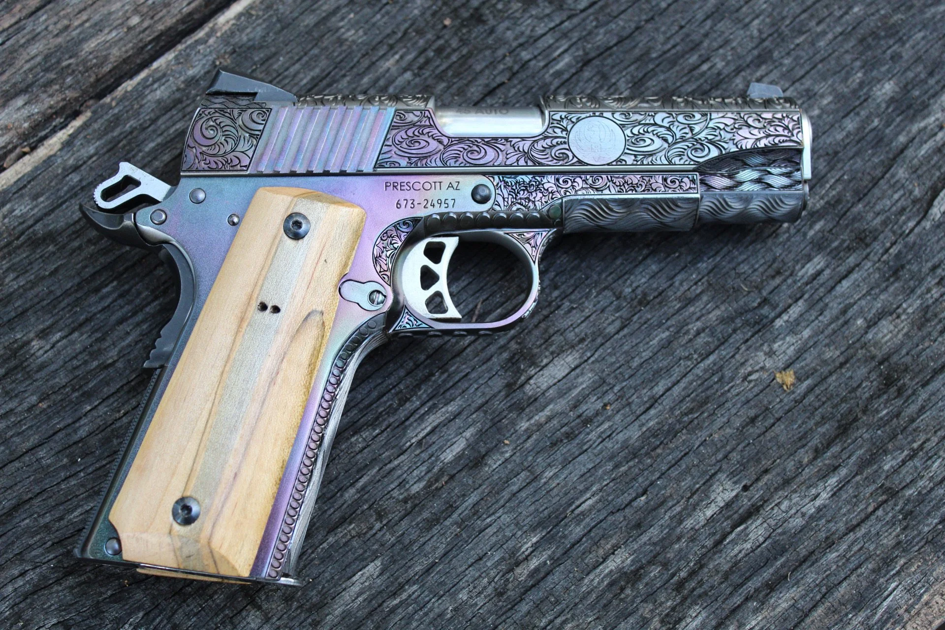 One-of-a-kind Ruger® 1911 featuring intricate scroll engraving, iridescent metal finish, and wood grip panels, custom designed and engraved for a client.