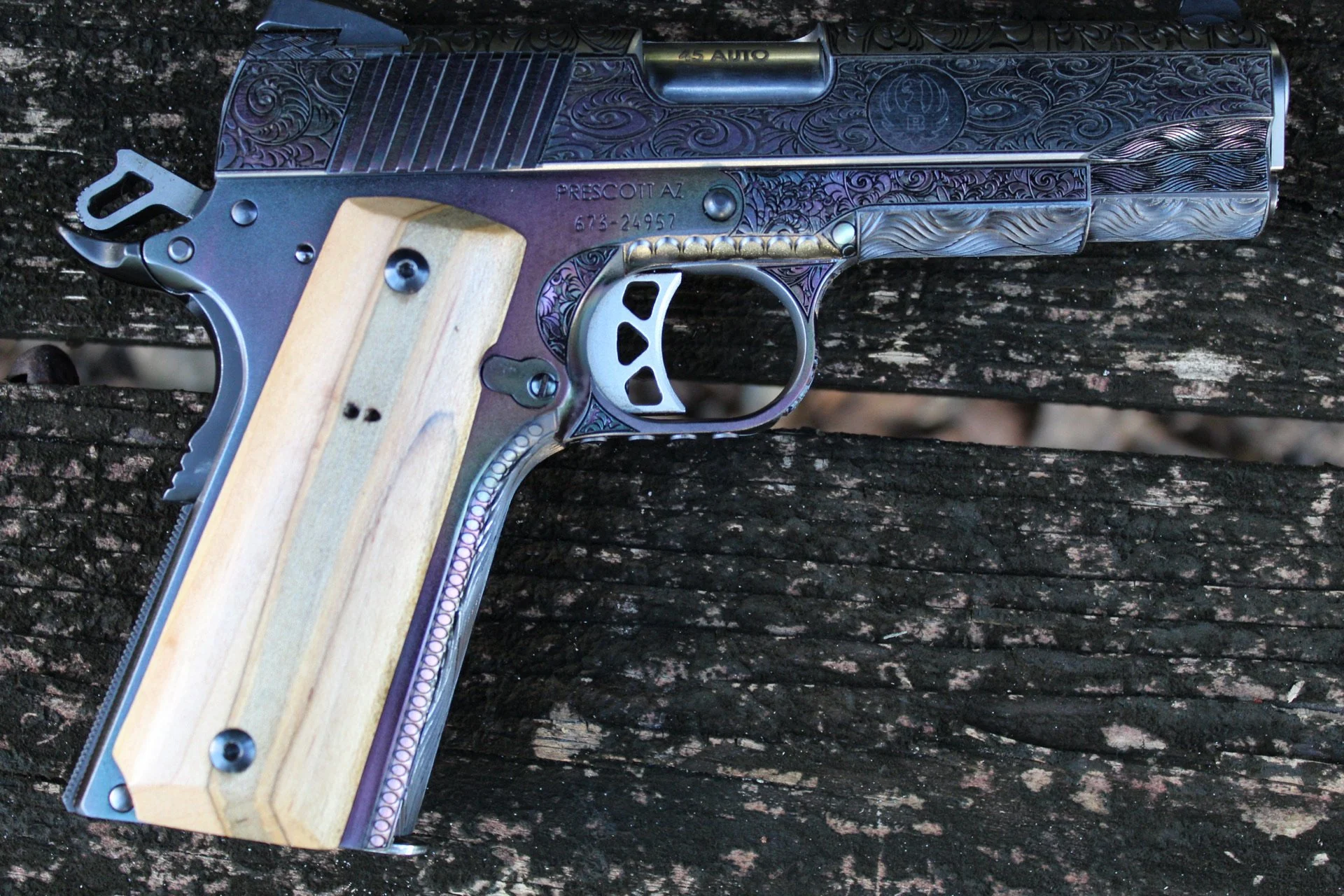 One-of-a-kind Ruger® 1911 featuring intricate scroll engraving, iridescent metal finish, and wood grip panels, custom designed and engraved for a client.