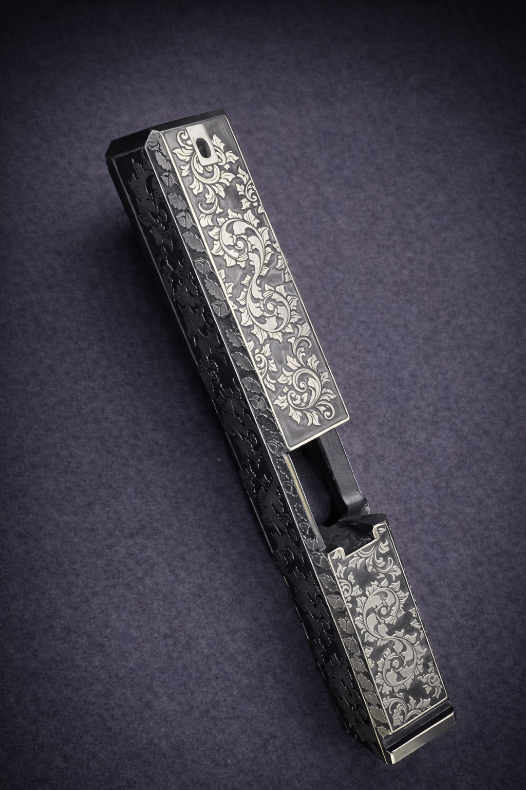 Custom Glock® 17 Gen 5 slide featuring deep engraved, ornate scroll engraving and dark Cerakote backfill finish.