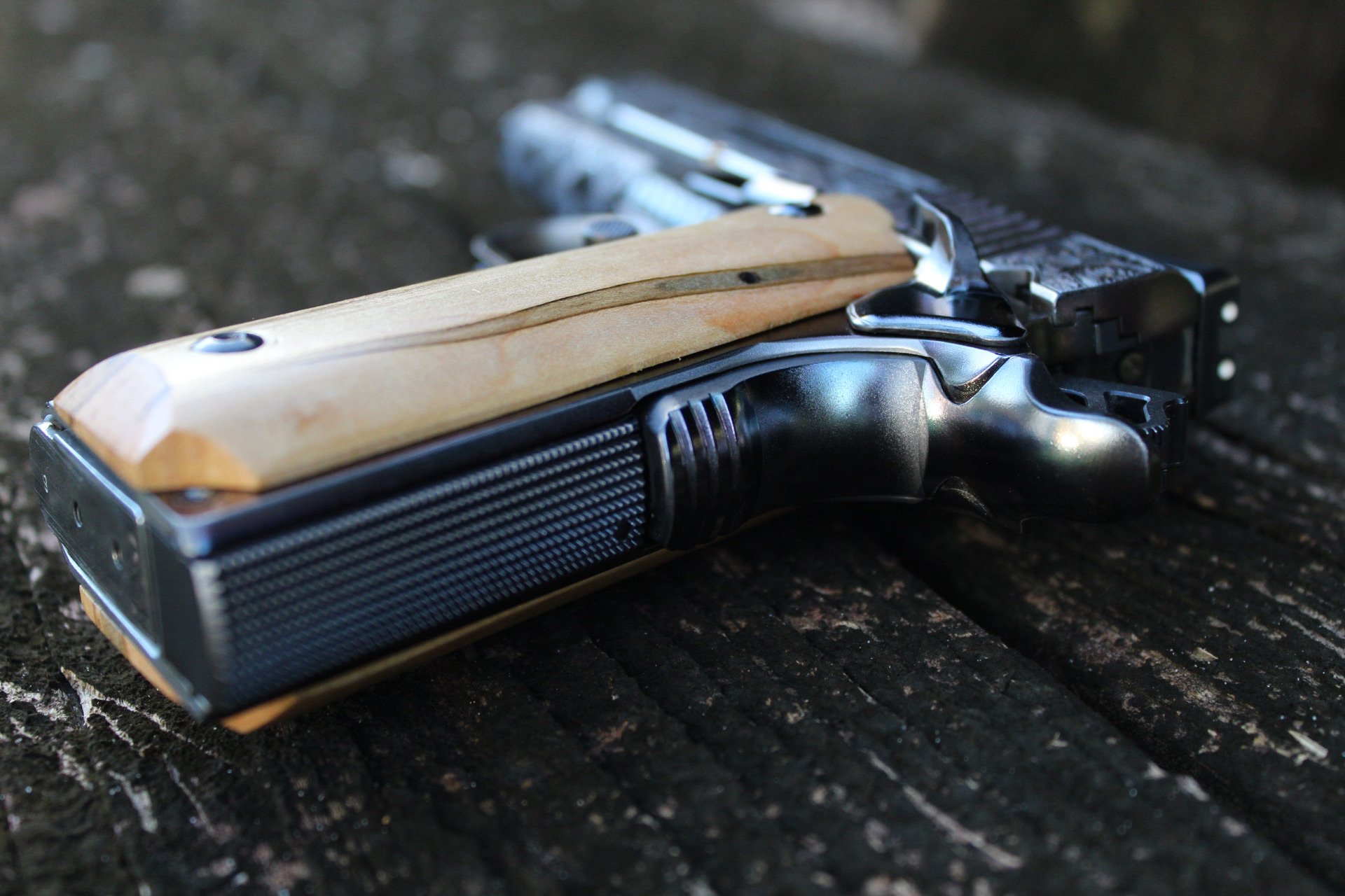One-of-a-kind Ruger® 1911 featuring intricate scroll engraving, iridescent metal finish, and wood grip panels, custom designed and engraved for a client.