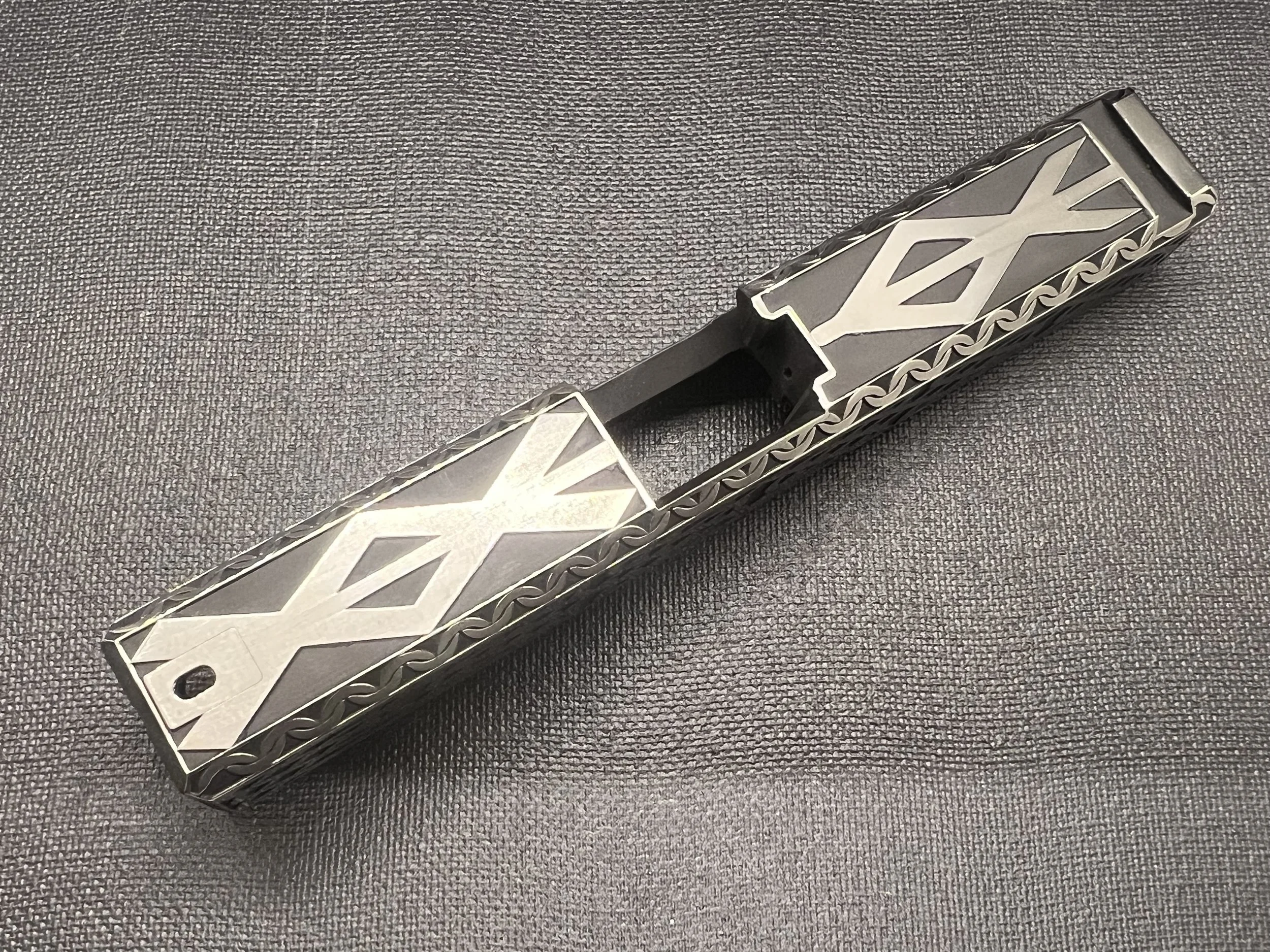 Custom engraved firearm slide featuring detailed Celtic knot pattern engraving with a dark Cerakote finish, showcasing precision laser craftsmanship.