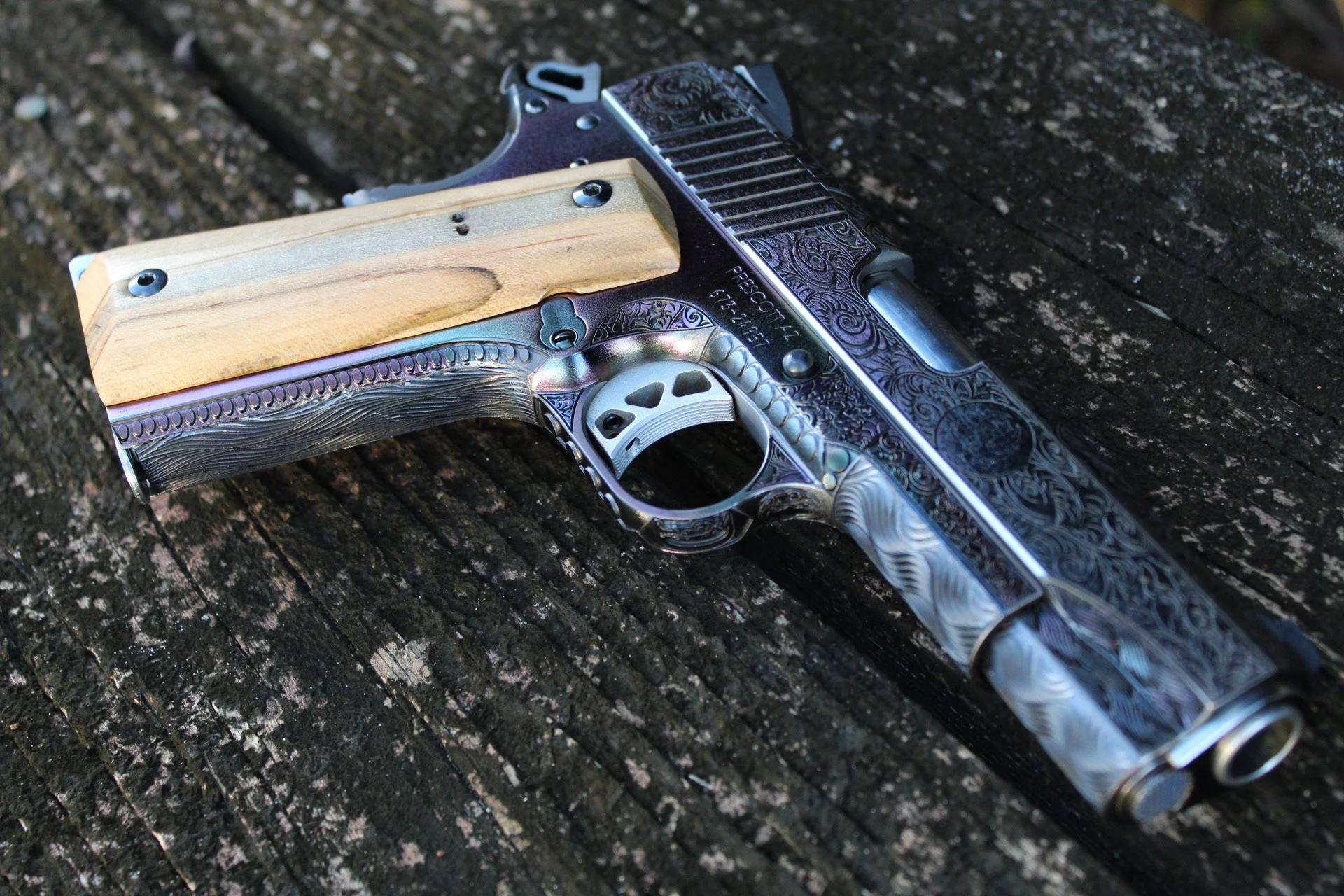 One-of-a-kind Ruger® 1911 featuring intricate scroll engraving, iridescent metal finish, and wood grip panels, custom designed and engraved for a client.