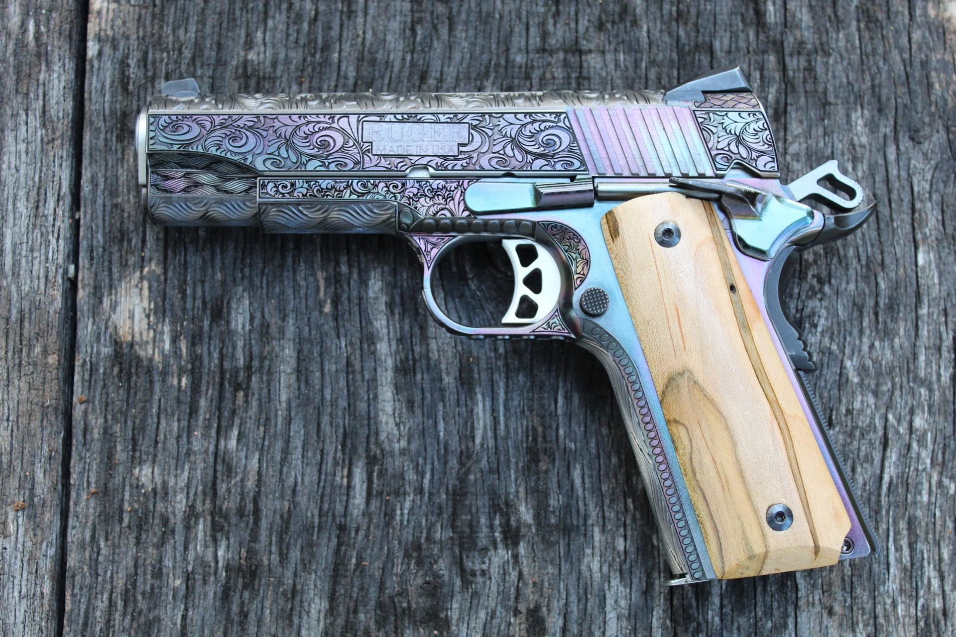 One-of-a-kind Ruger® 1911 featuring intricate scroll engraving, iridescent metal finish, and wood grip panels, custom designed and engraved for a client.