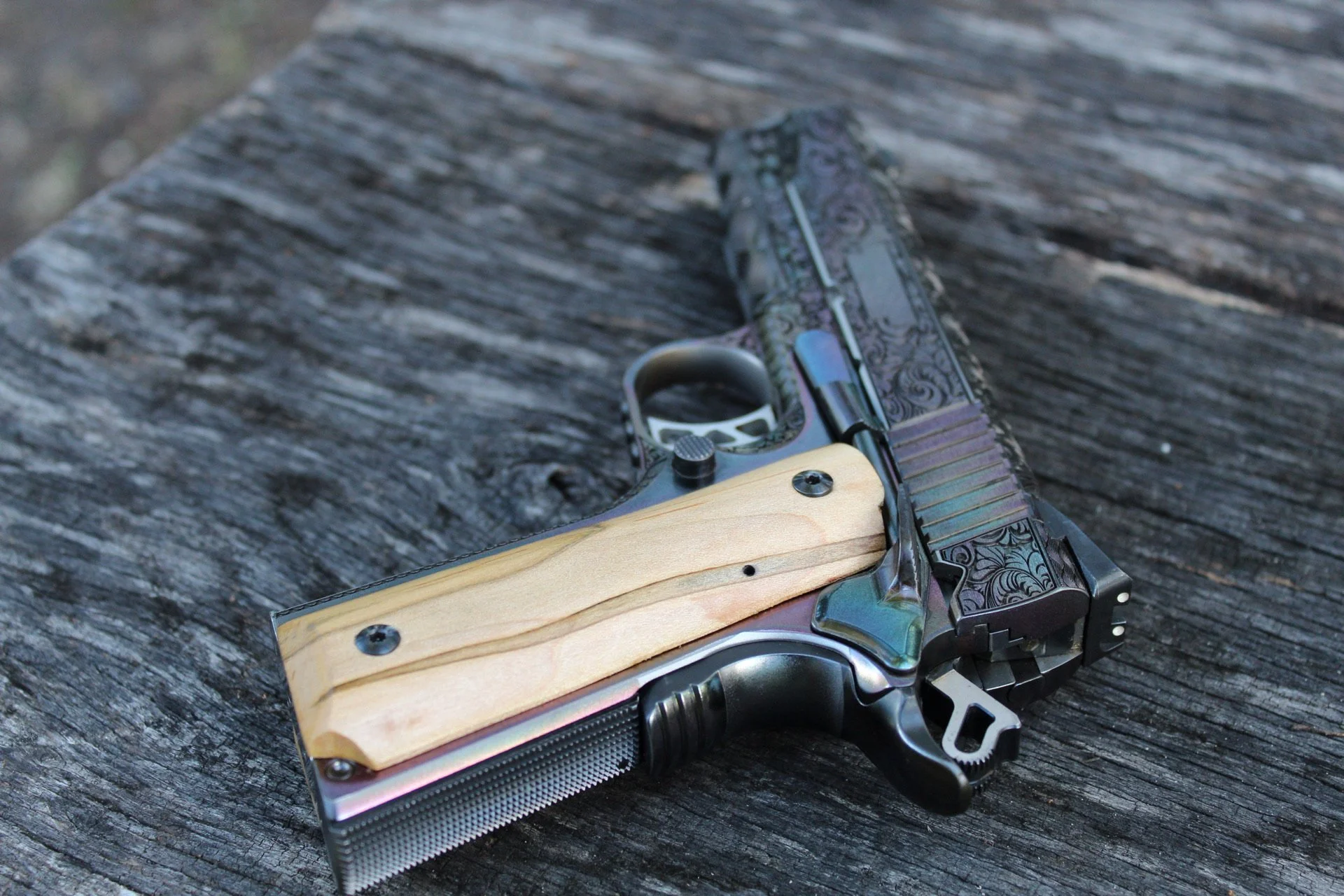 One-of-a-kind Ruger® 1911 featuring intricate scroll engraving, iridescent metal finish, and wood grip panels, custom designed and engraved for a client.