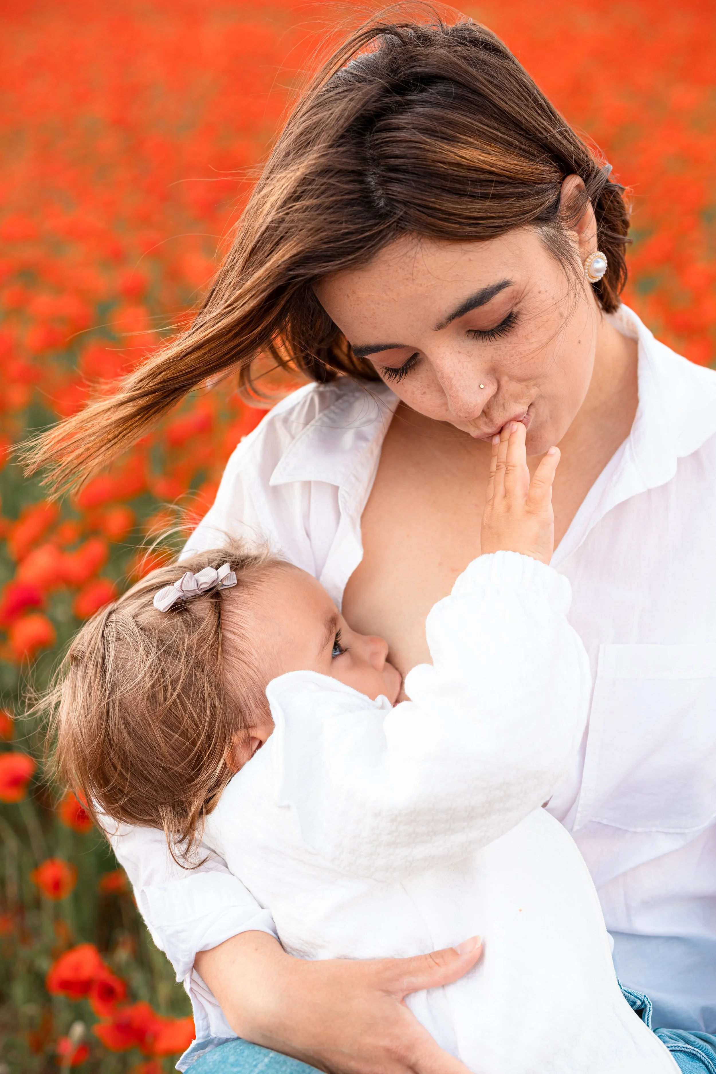 Une femme et une petite fille dans un champ de coquelicots, la femme fait un bisou sur le doigt de la fille qui semble lui faire un doigt d'honneur.