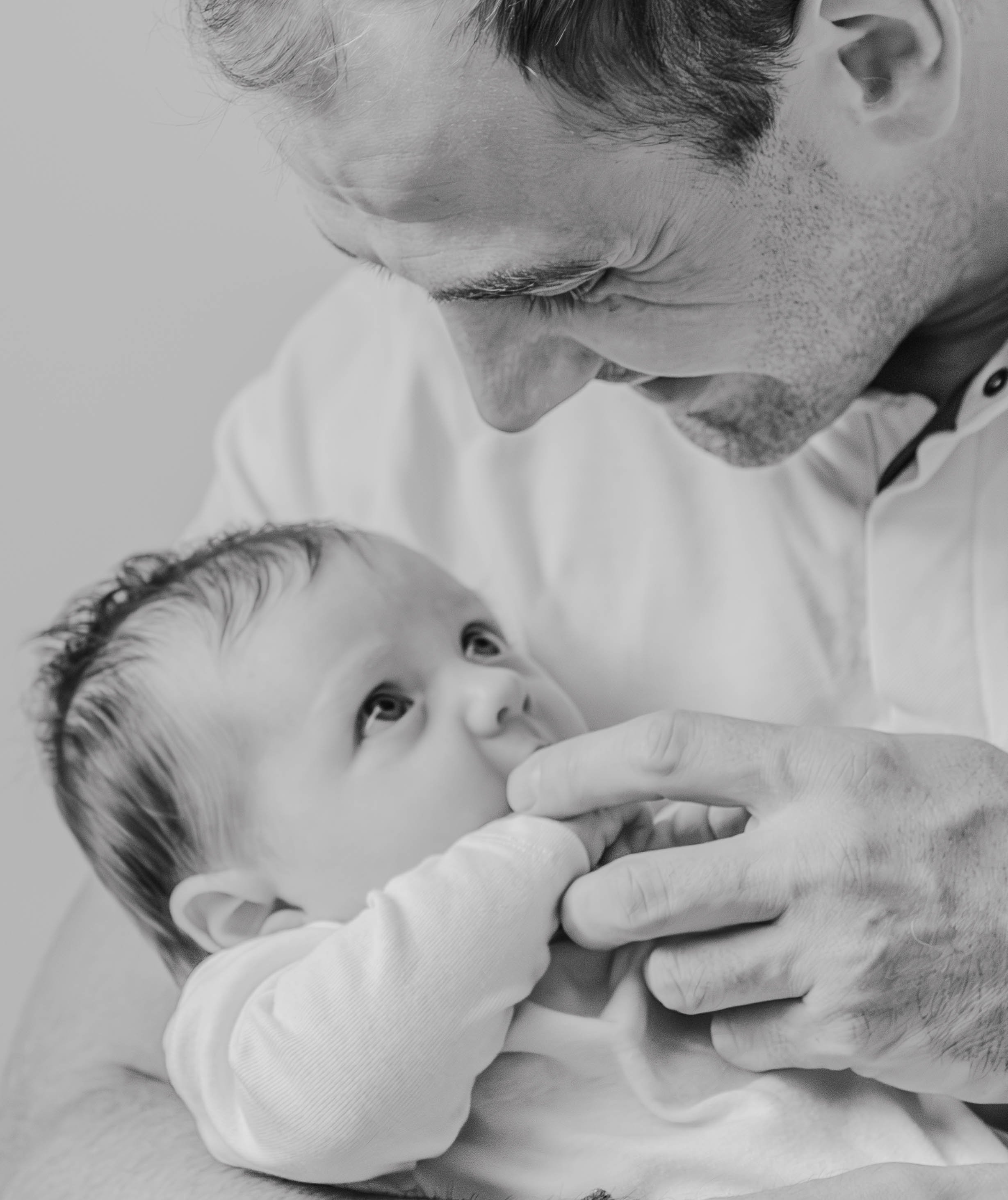 Un homme adulte tenant un bébé dans ses bras, regardant le bébé avec affection.