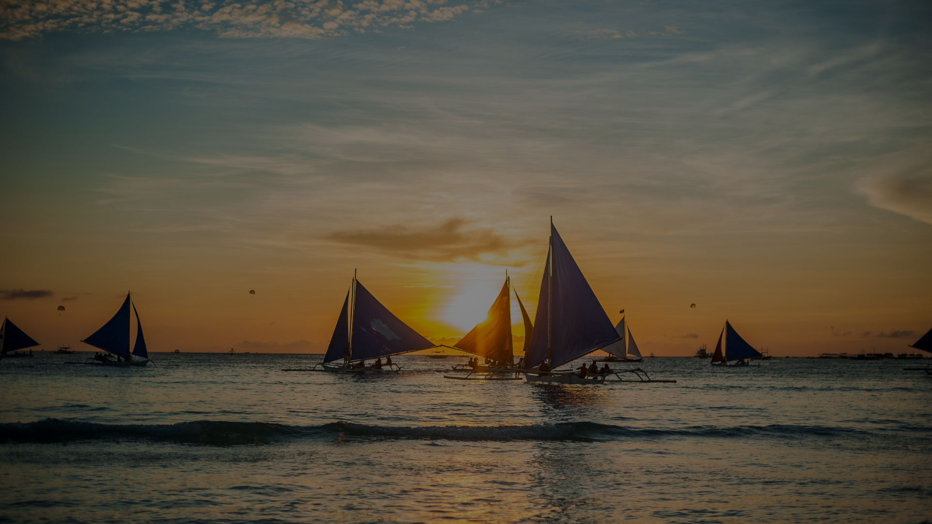 Sailboats on Boracay’s White Beach at sunset with golden light reflecting on the sea.