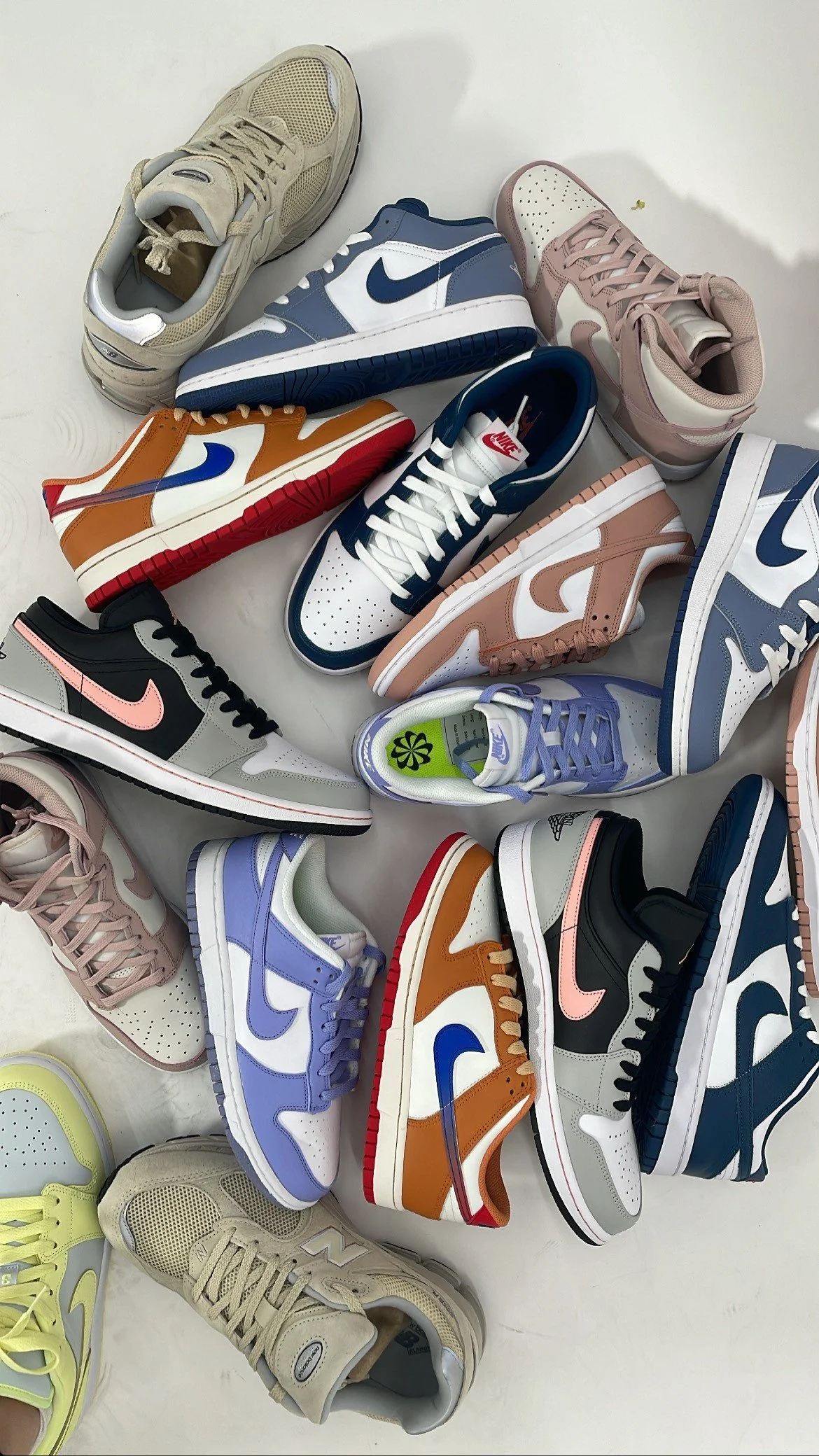 Several pairs of athletic sneakers in various colors arranged on a white surface.