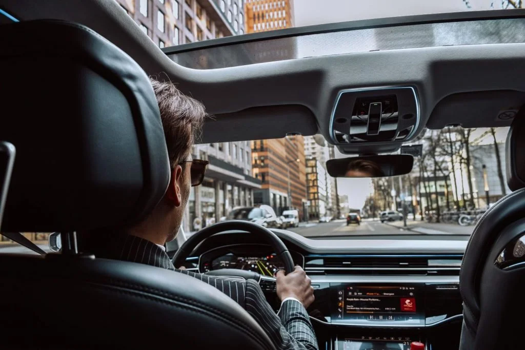 Binnenkant van een auto met een privéchauffeur, met een stadsgezicht buiten de auto.