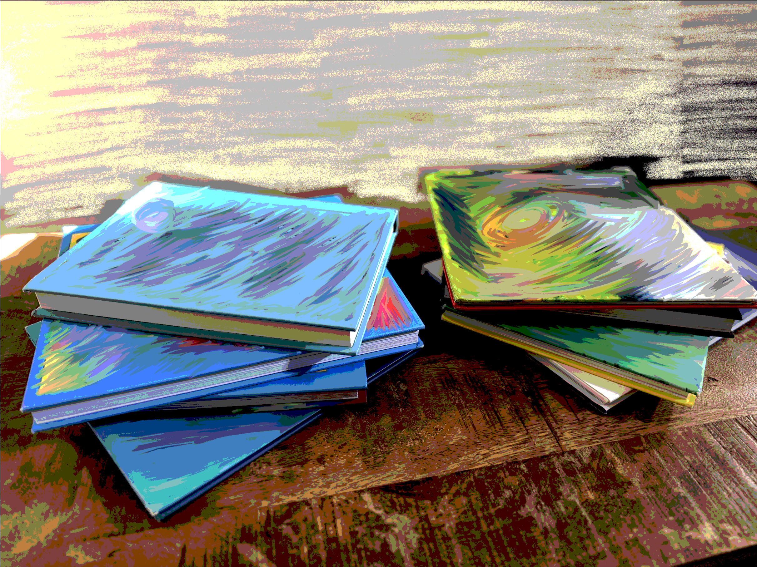 Stacks of painted art books on a wooden table with a textured, neutral background.