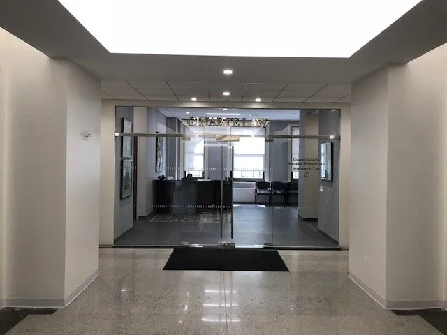 Entrance to a law firm named 'Ginarte Law' with glass doors and a waiting area inside.