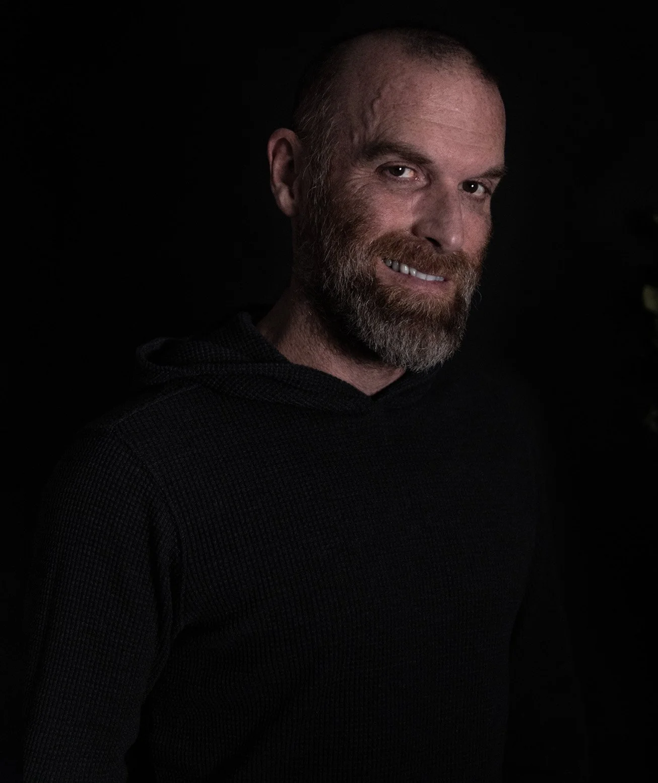 Portrait de Stéphane-Thomas Durocher en lumière tamisée sur fond noir — coach certifié en PNL, spécialisé en intelligence émotionnelle et évolution humaine.