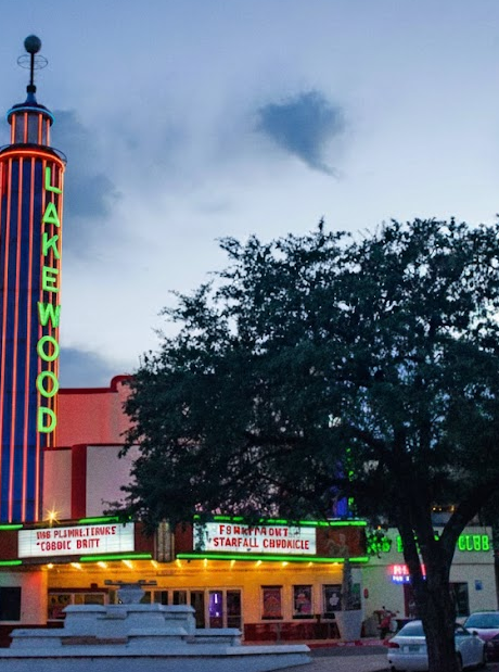 The Lakewood theater marquee with neon lights, a large tree in front, and a cloudy sky above.