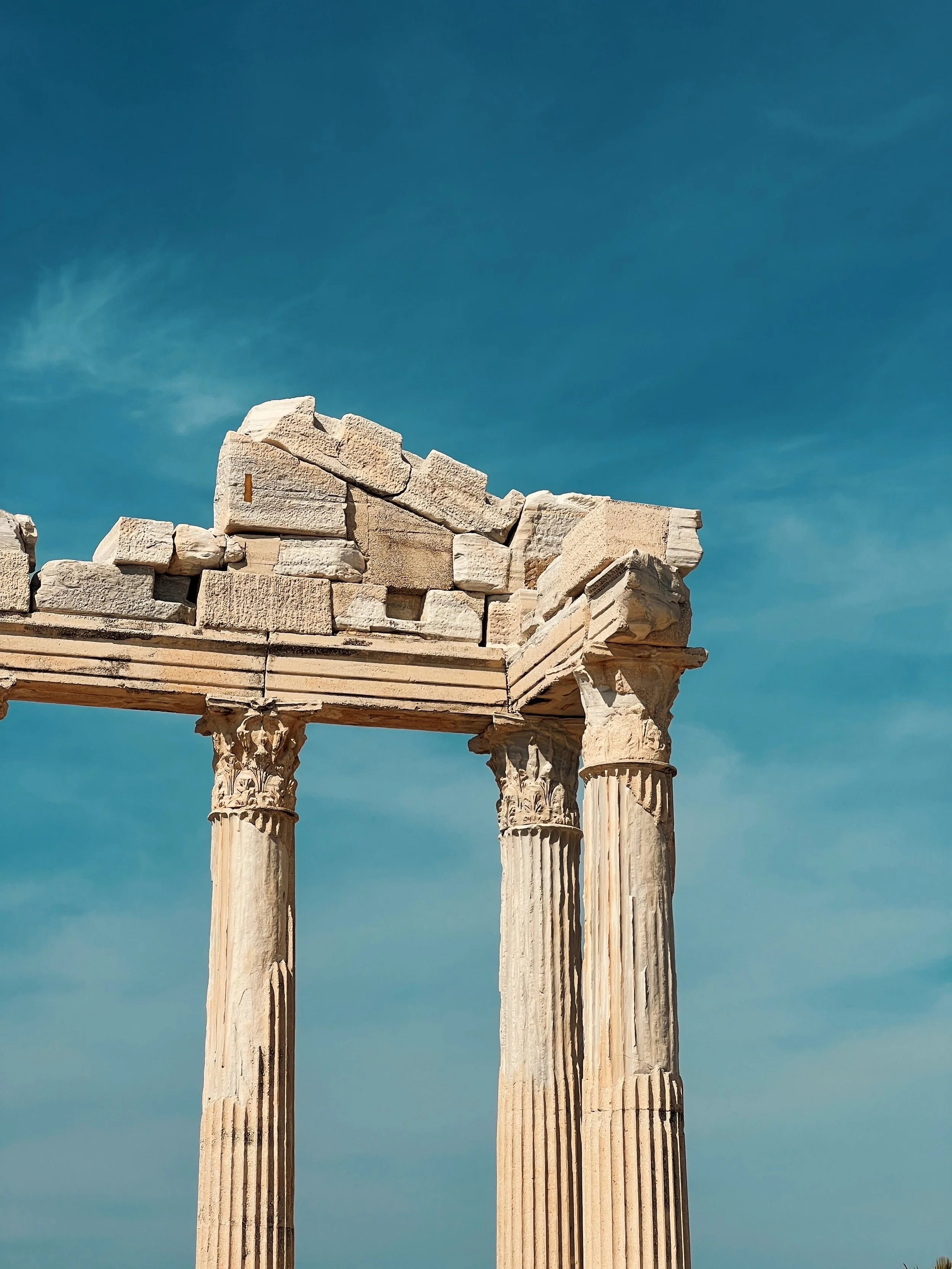 Restes de colonnes antiques et ruines en pierre contre un ciel bleu.