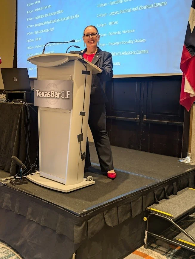 An appellate lawyer is standing at the TexasBarCLE podium presenting MCLE. She is wearing a navy suit.