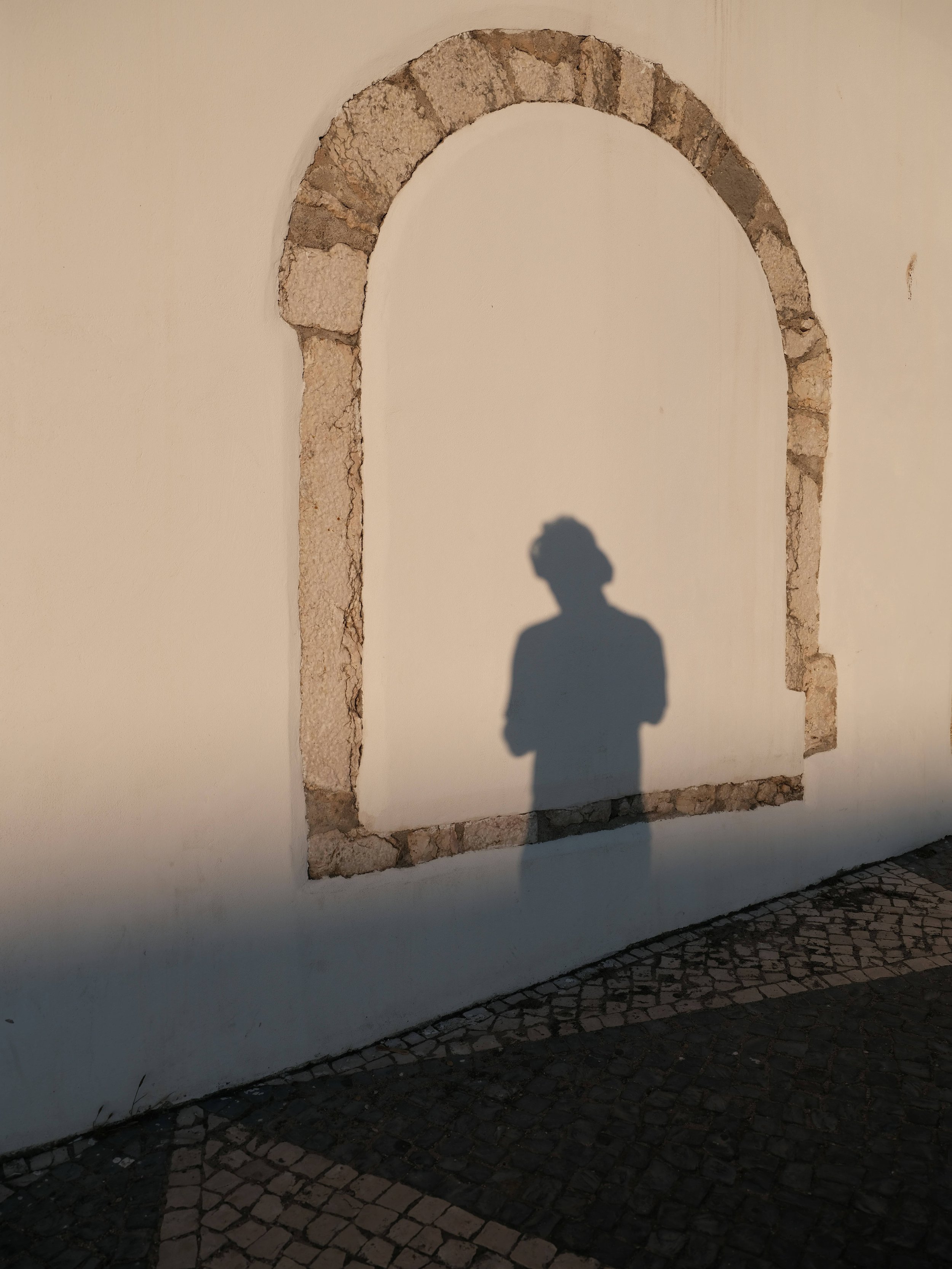 Teen silhouette framed in an arch on a stucco wall.