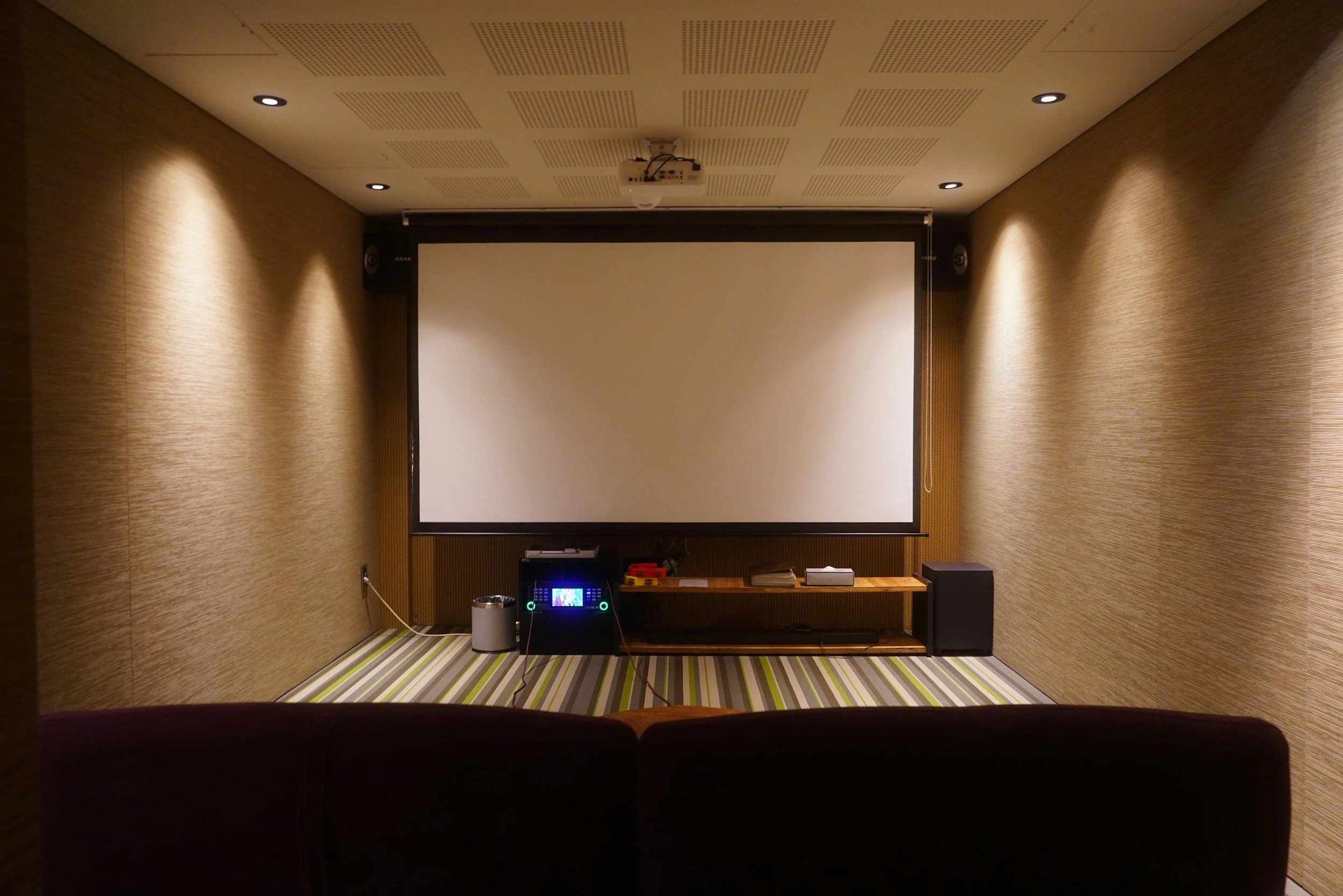 Empty home theater with a large projection screen, audio equipment, and a patterned floor