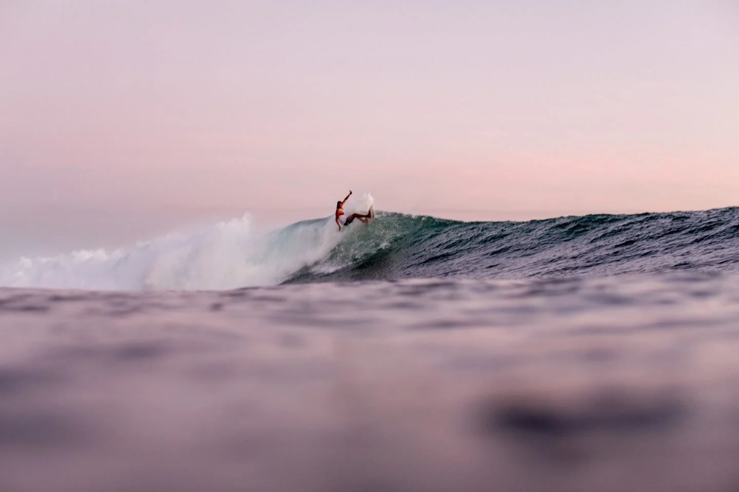 Surfer riding a wave at sunset, capturing the essence of a coastal surf experience