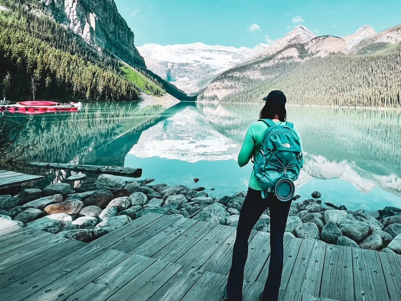 Traveler overlooking a mountain lake during an adventure experience, reflecting the type of curated journeys designed by Latitude Lens