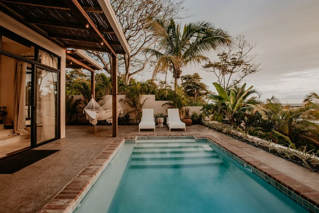 Tropical pool at a boutique property surrounded by lush greenery, representing curated travel accommodations