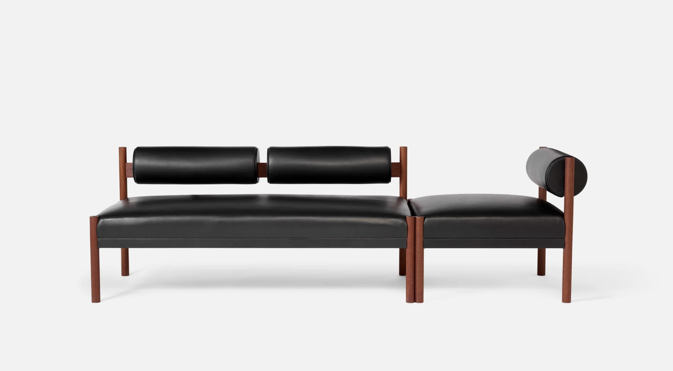 Modern black leather sectional sofa with wooden frame and cylindrical armrests on a plain white background.
