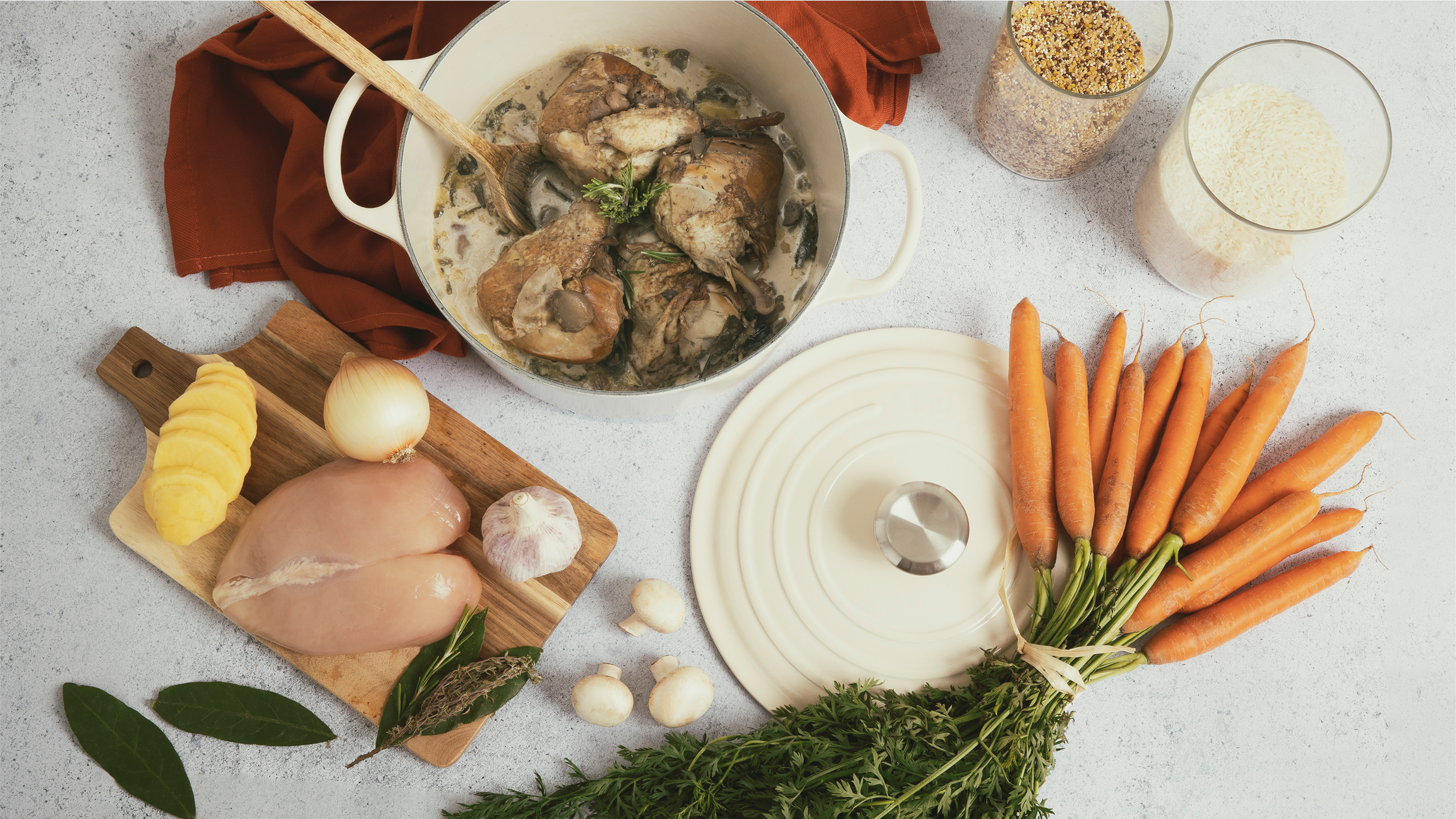 Ingrédients de poulet avec légumes et riz, avec un plat de poulet en sauce, carottes, oignons, ail, épices, et riz râpé, tous disposés sur une surface de cuisine