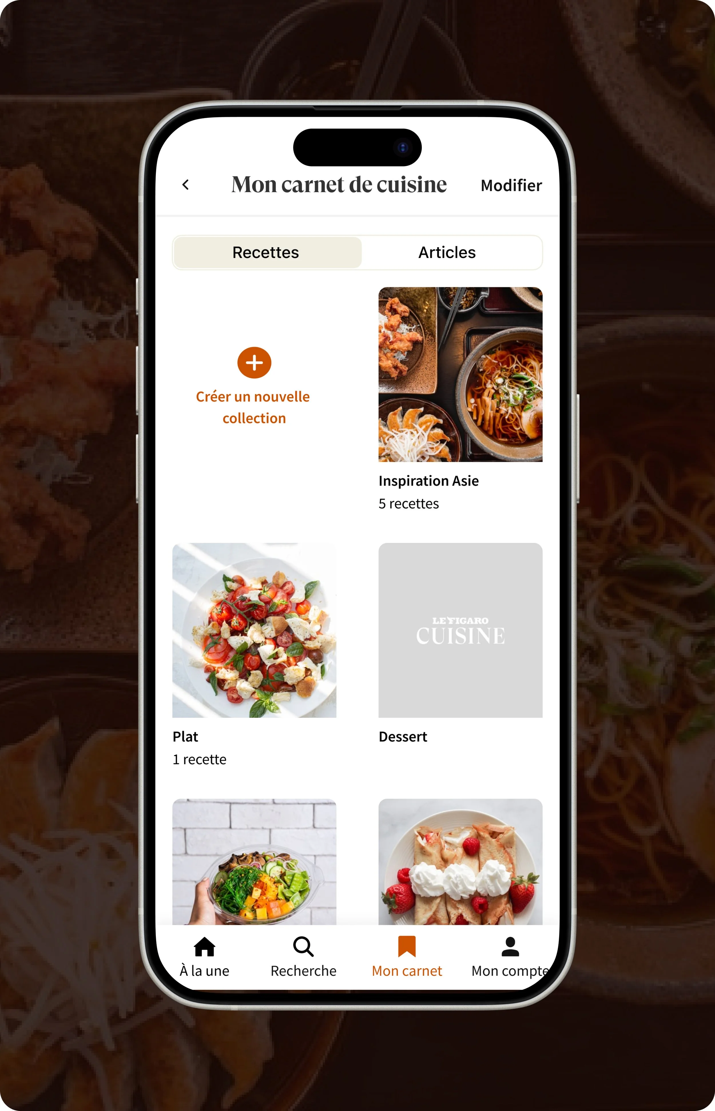 Capture d'écran d'une application de cuisine avec une section 'Mon carnet de cuisine', montrant des collections de recettes inspirées de la cuisine asiatique, accompagnée de photos de plats. La partie visible montre une collection nommée "Inspiration Asie" avec 5 recettes, une photo de salade colorée, et une photo de gâteau avec des fraises.