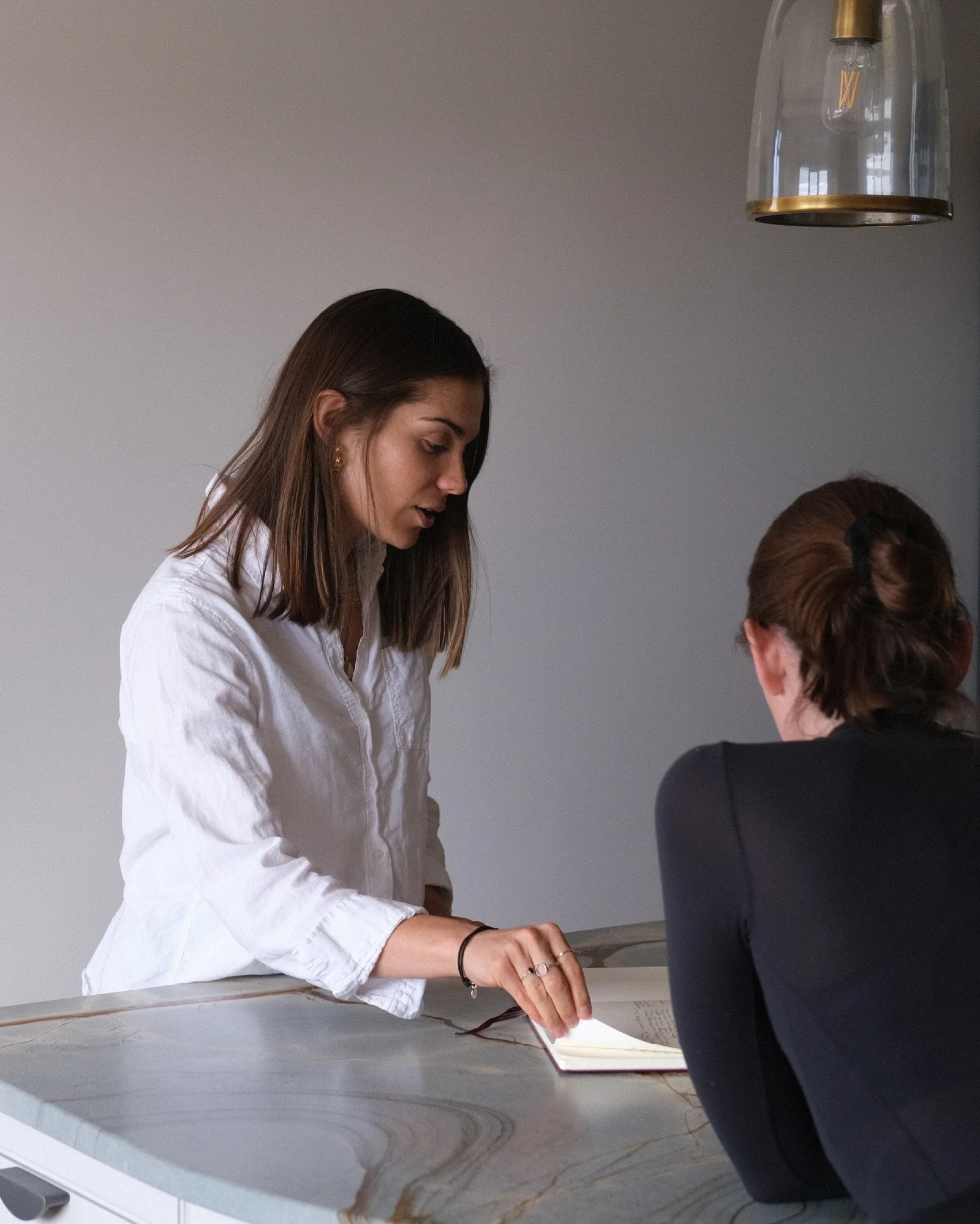 Georgina Howell in person with a client, talking them through information in a notebook.