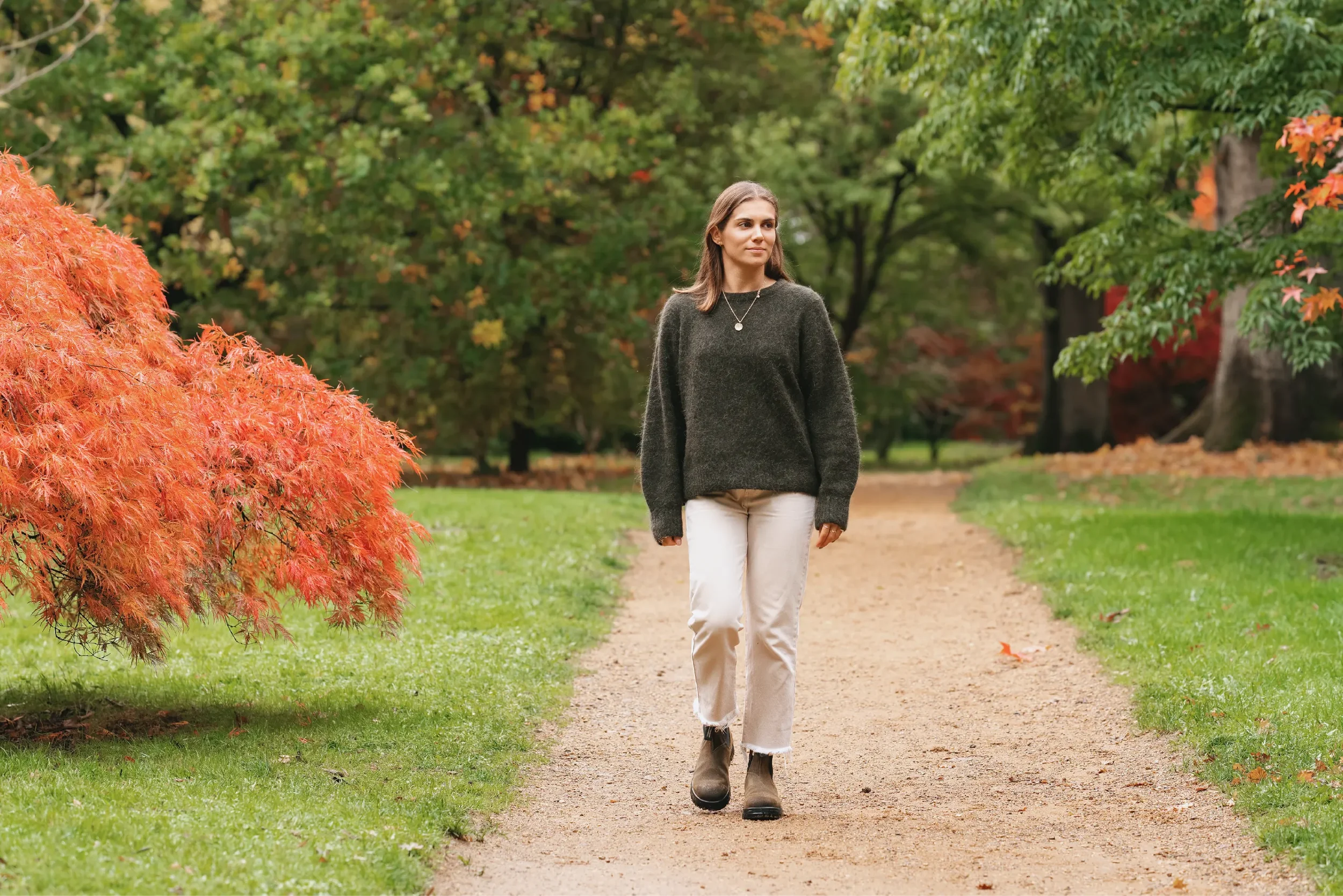 Georgina Howell walking down a path, surrounded by autumnal trees