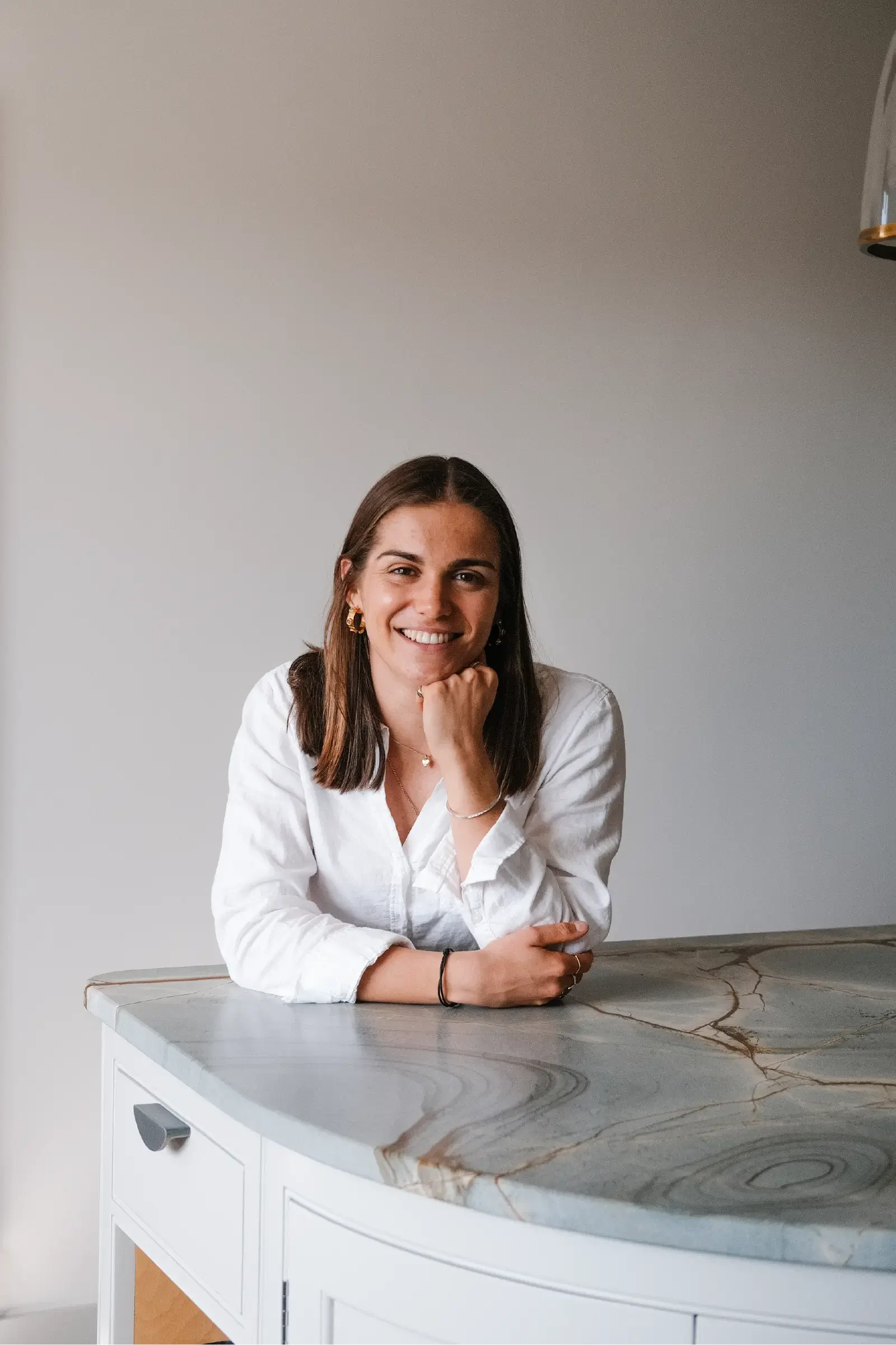 Portrait of Georgina Howell leaning against counter with chin resting on fist