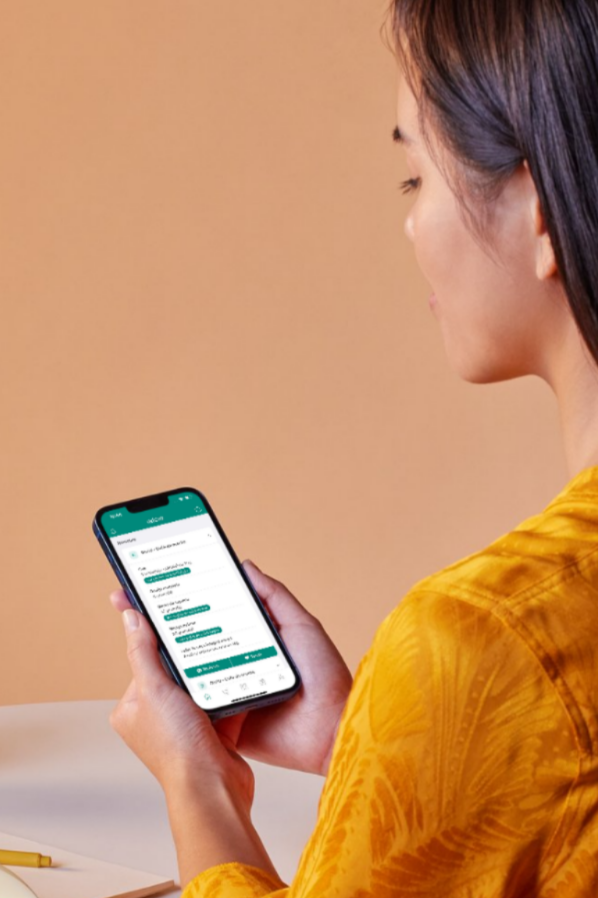 Mulher com blusa amarela segurando um celular, visualizando um aplicativo de mensagens.