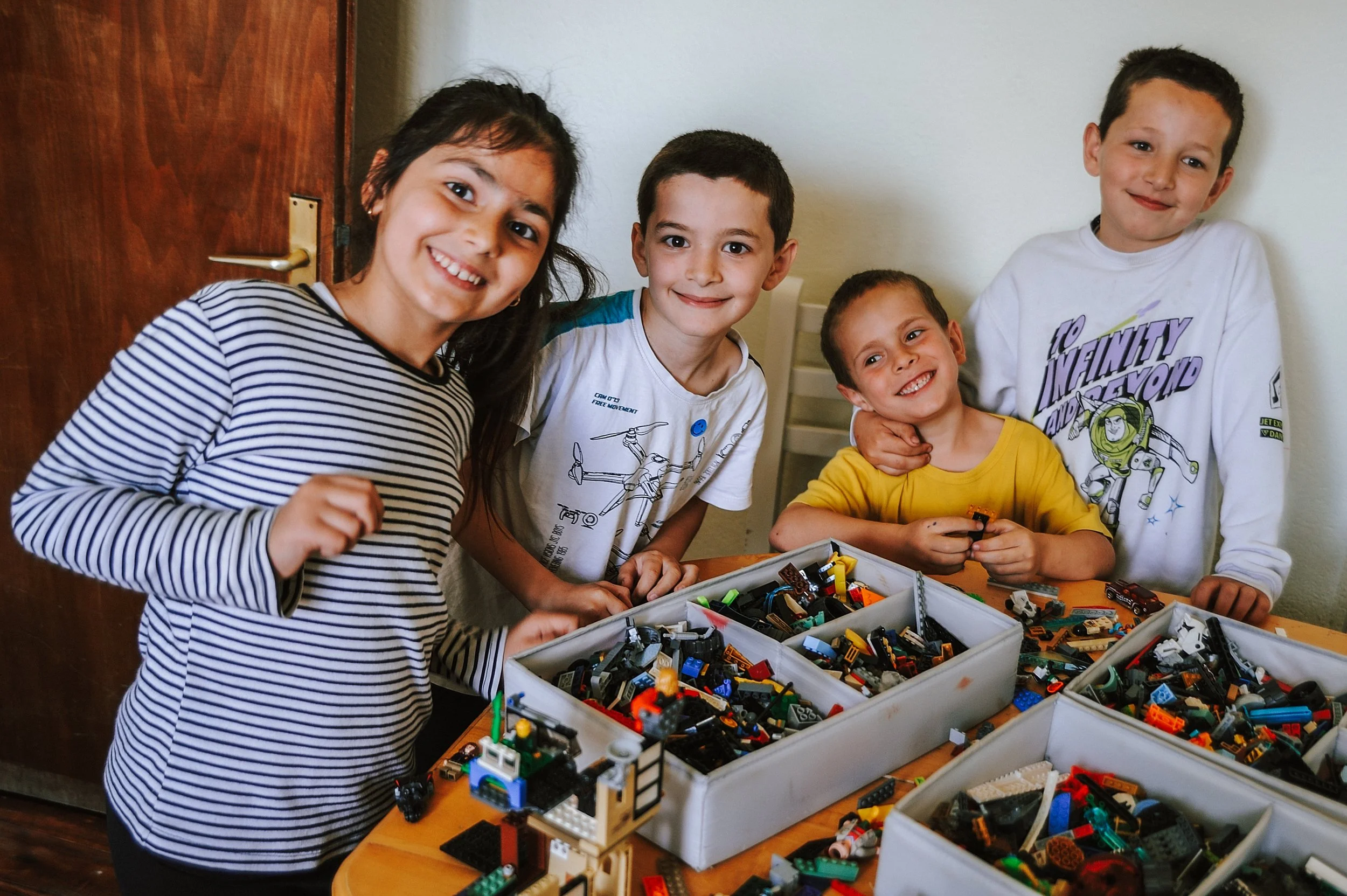 Fünf Kinder spielen mit Lego-Bausteinen auf einem Tisch.