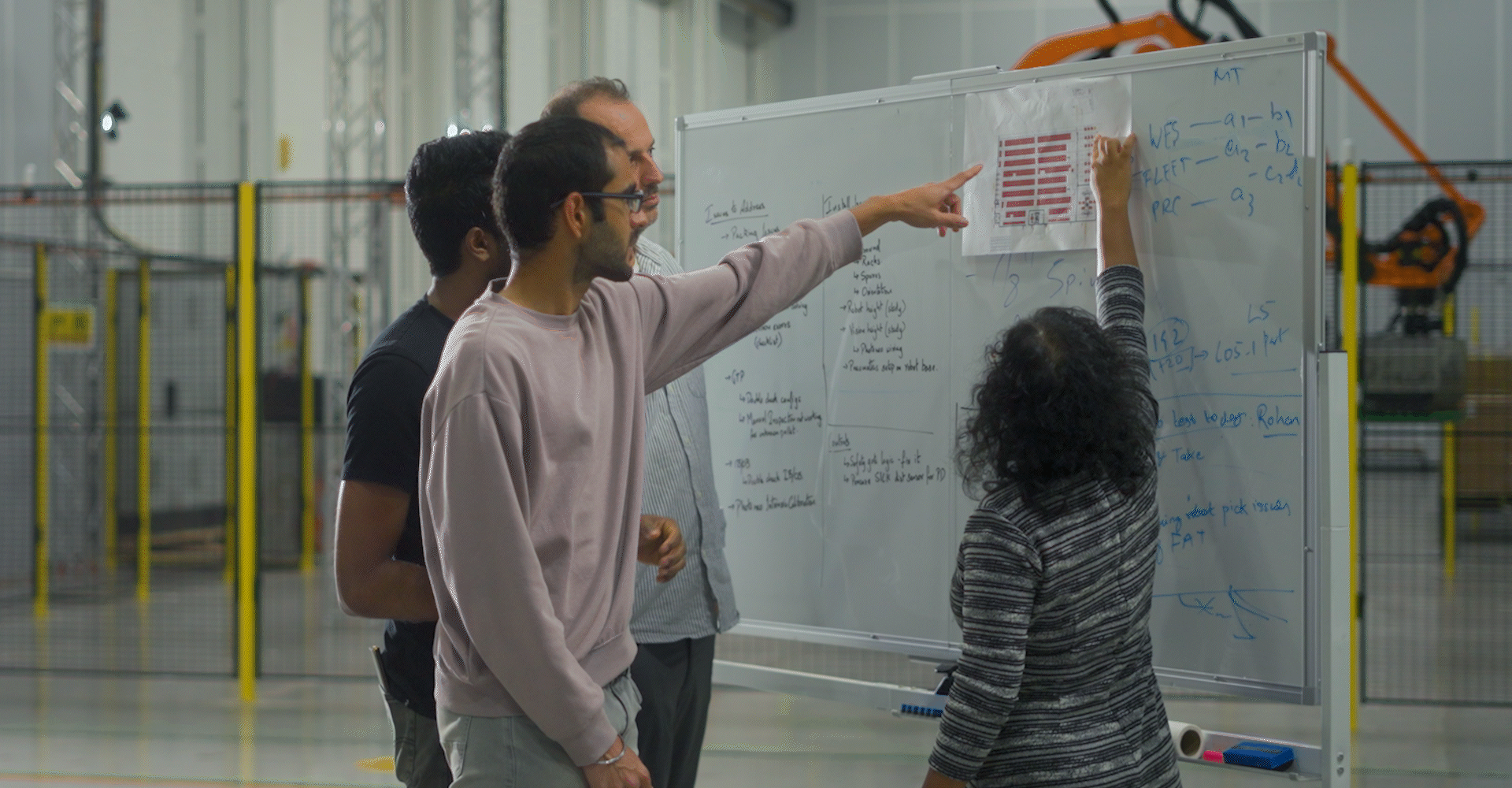 A modern wooden house on a grassy hillside with a view of a lake and distant mountains in the background, during sunset.