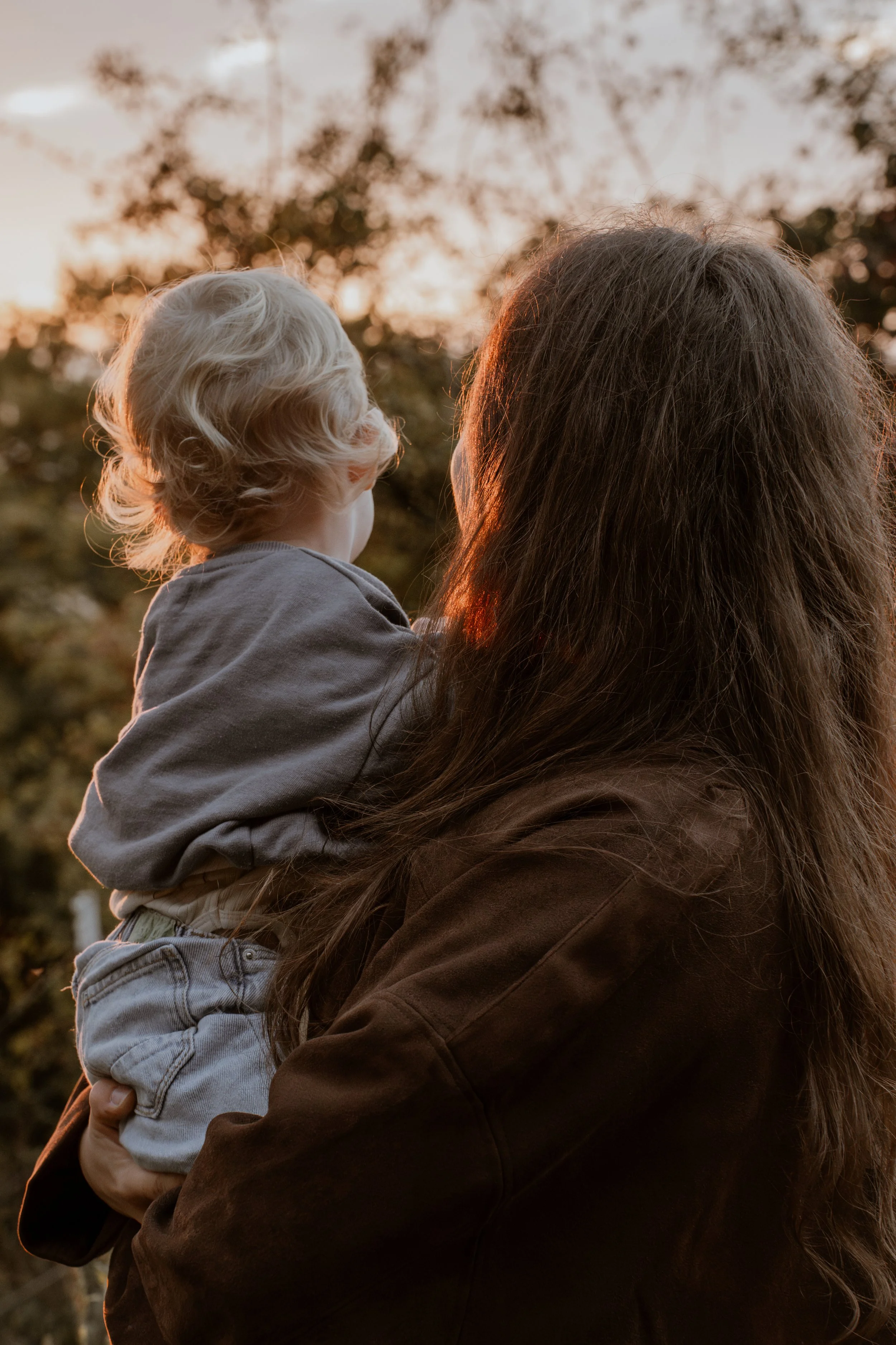 Mutter hält Kind auf dem Arm im Sonnenuntergang - natürliche Familienfotografie in Hannover