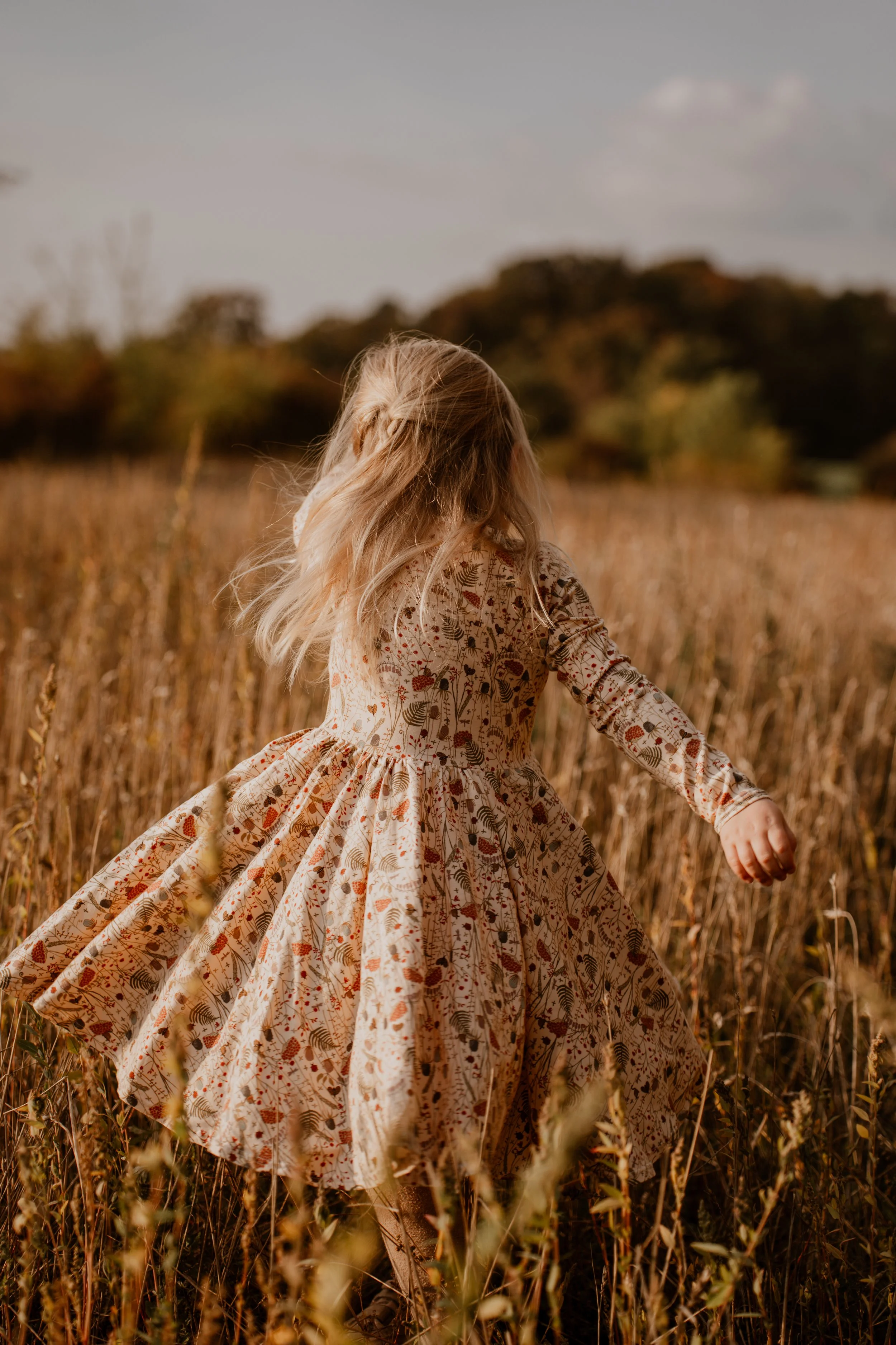 Kind dreht sich im Feld auf einer Wiese - authentische Familienfotografie in Hannover