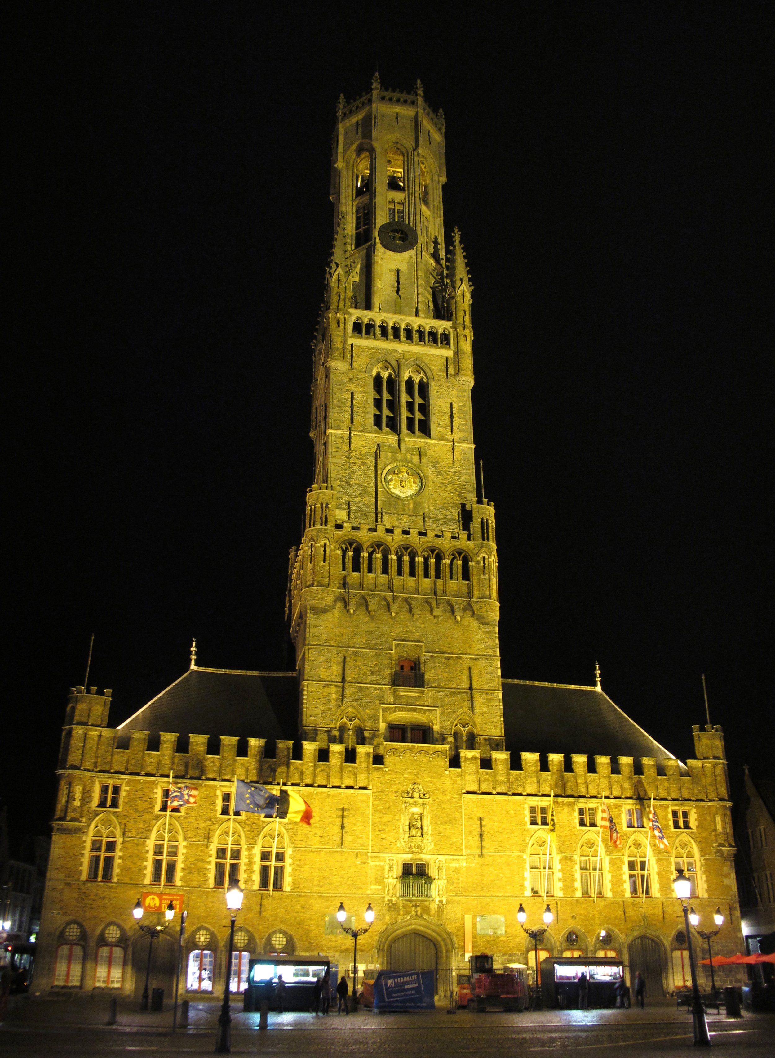 The illuminated medieval Belfry of Bruges at night, rising above the historic city centre in Belgium.