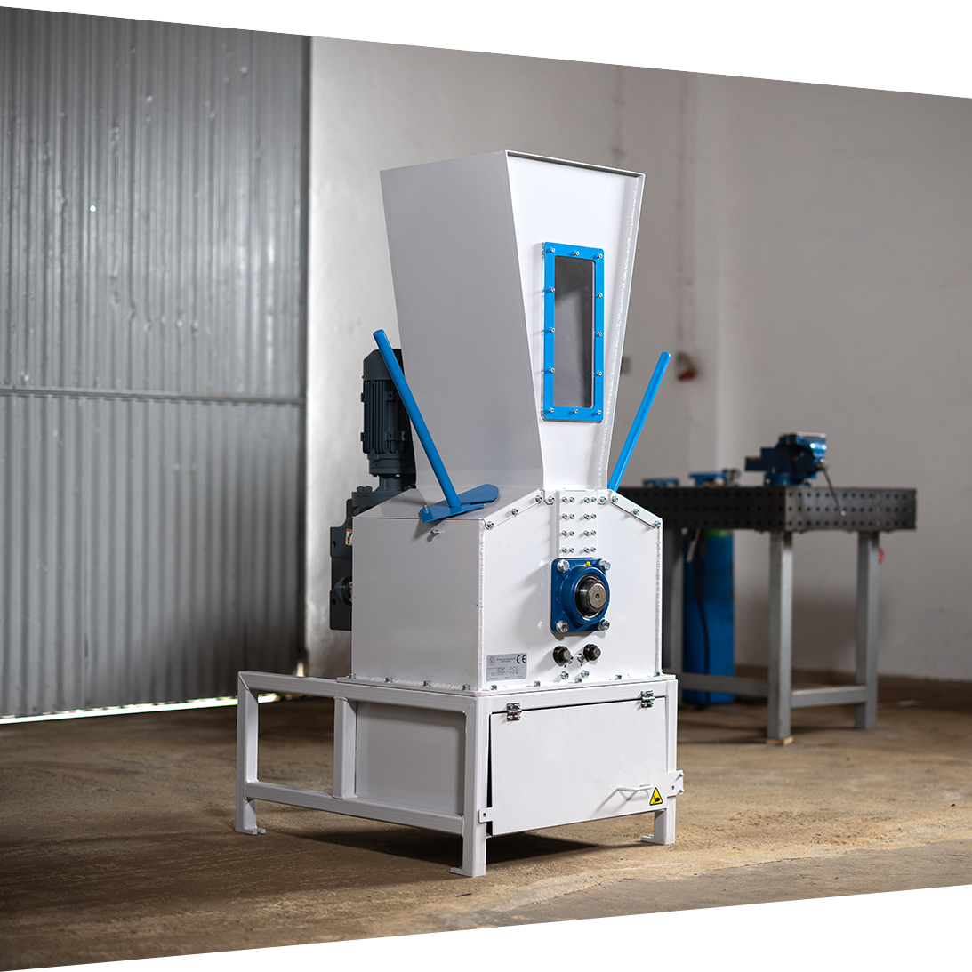 Industrial machine with a white metal body and blue accents, located in a workshop setting.