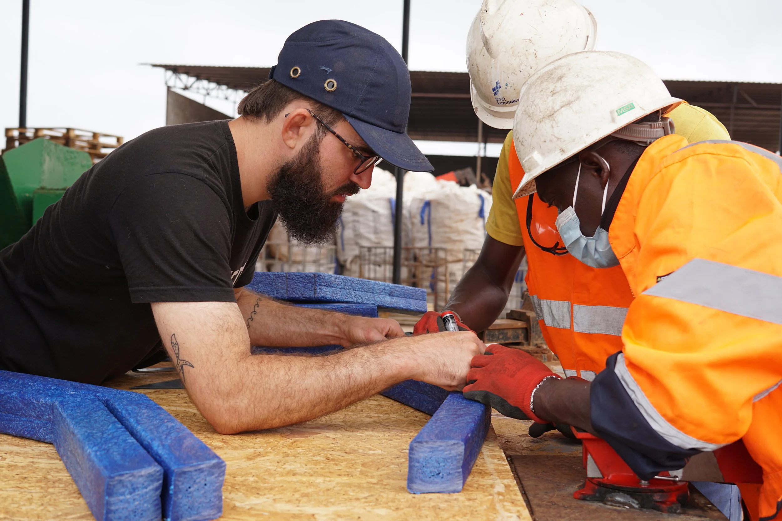 Yann is helping some newly trained plastic recyclers in Gabon with the construction and assembly of a bench made from recycled blue plastic.