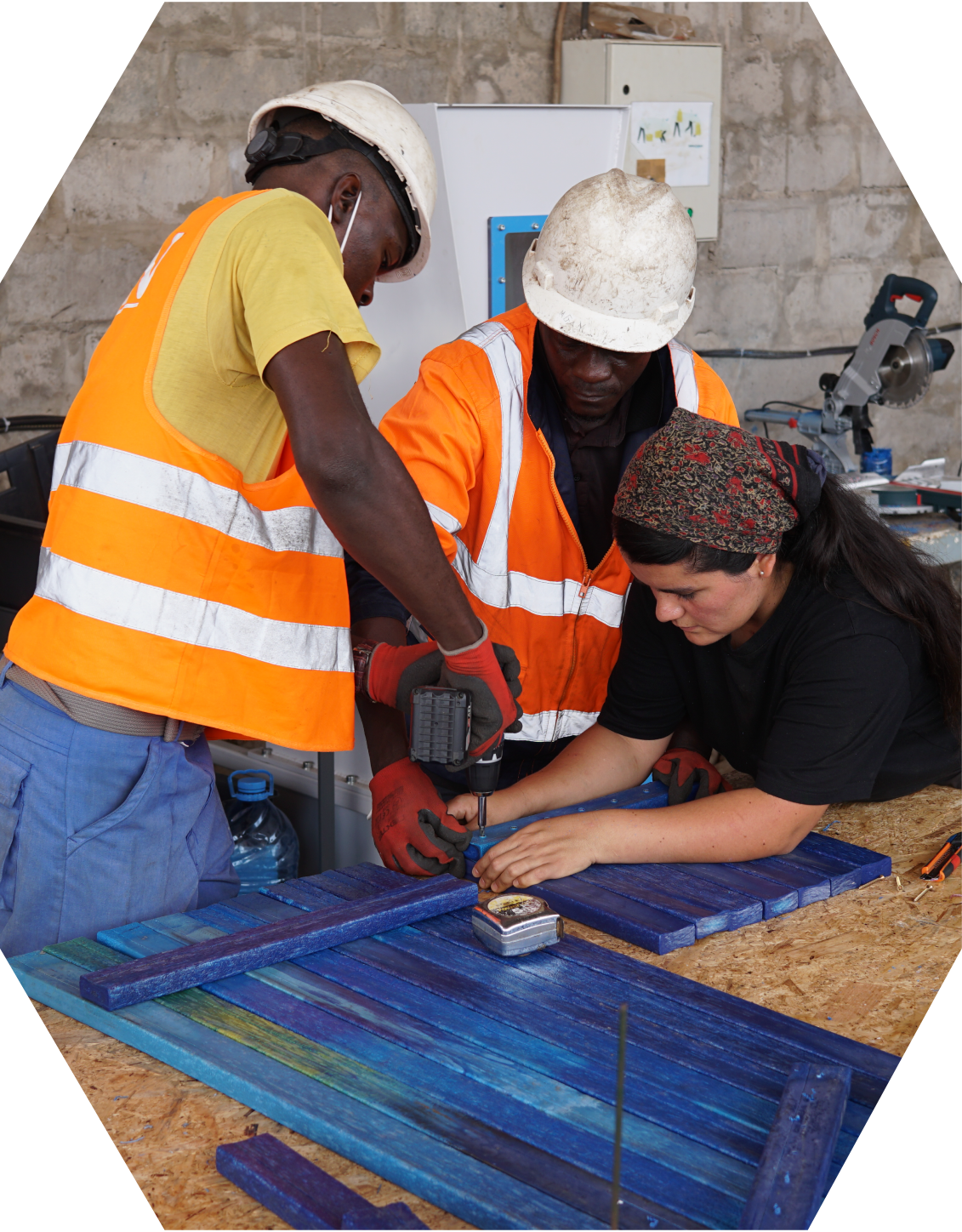 Caro helping newly trained plastic recyclers to make a bench out of recycled plastic beams in Gabon.