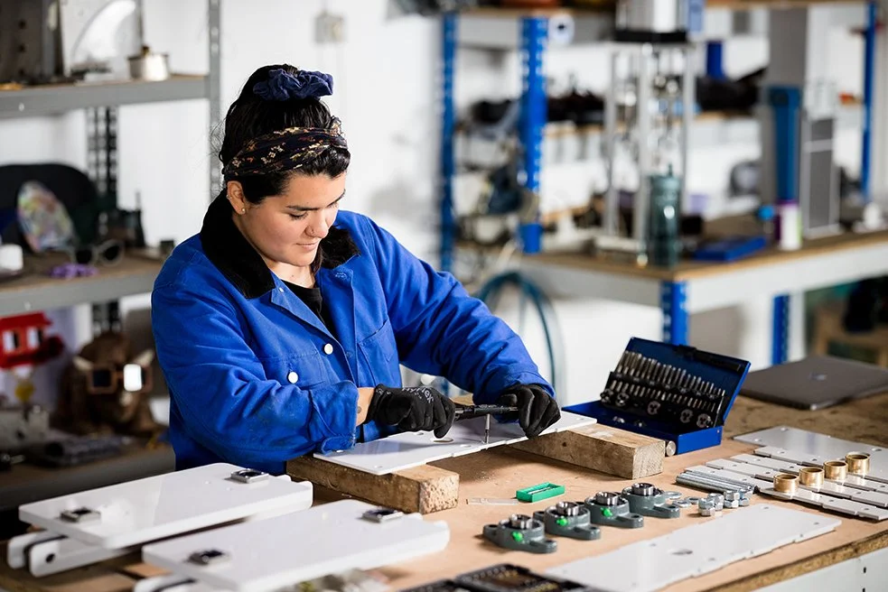 Caro assembling a machine with the different pieces laying in front of her.
