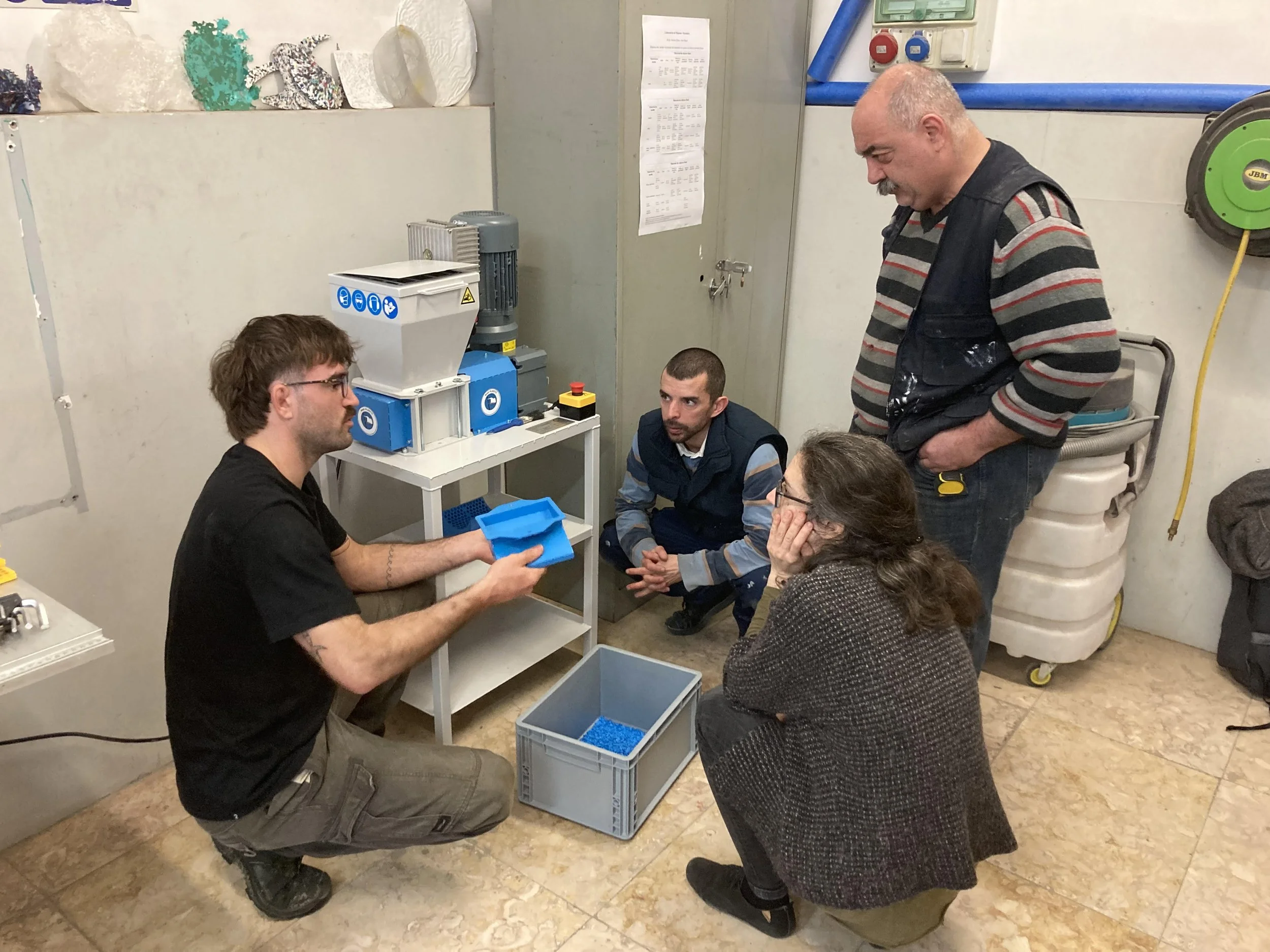 People gathered around a plastic shredder hearing explanation on how to use it