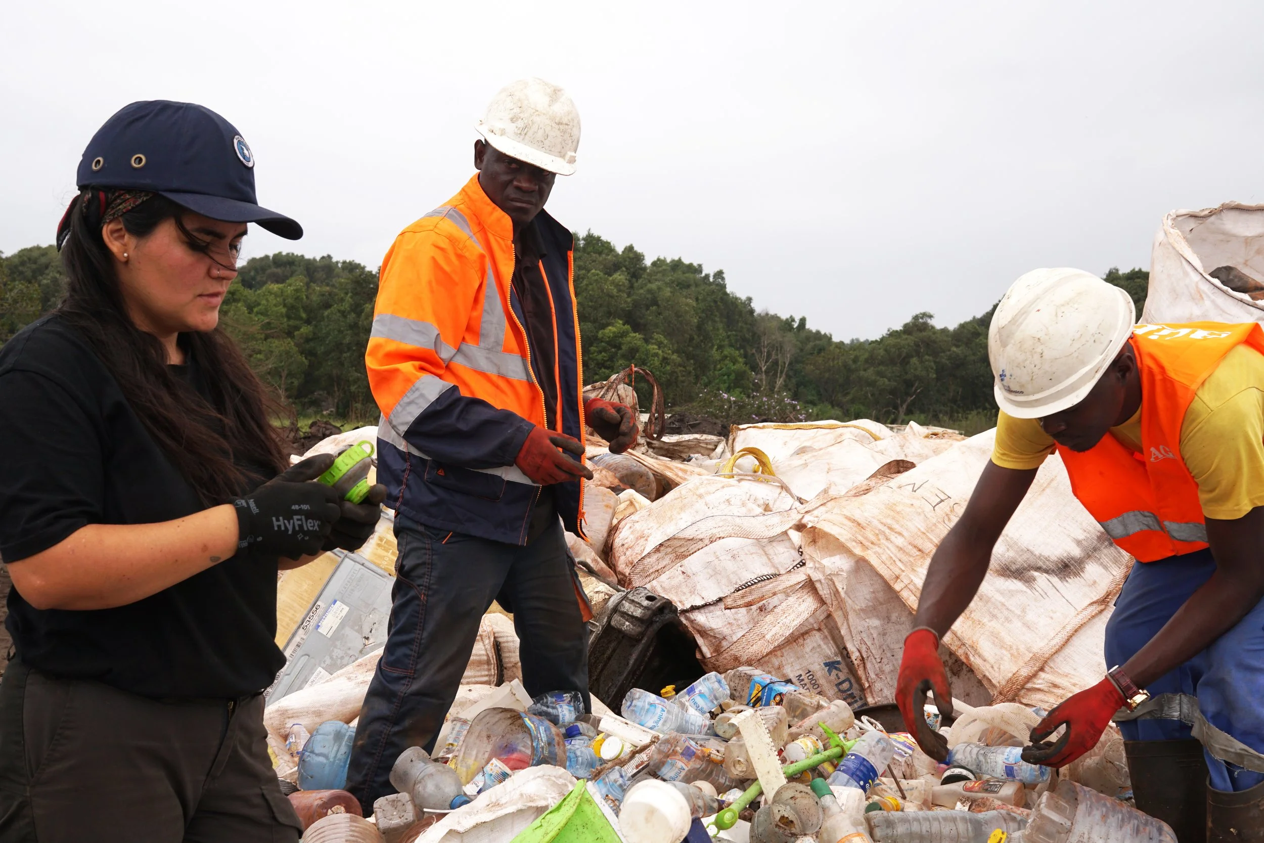 a group of people collecting and sorting plastic waste from a landfill