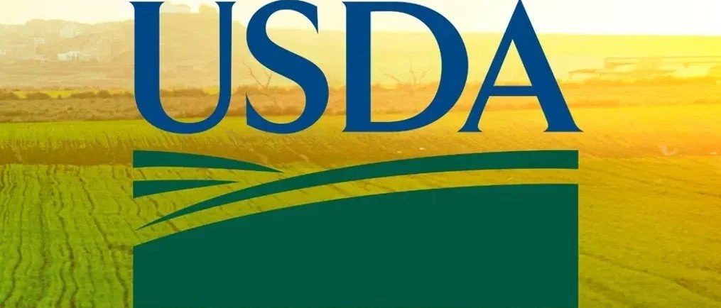 USDA logo over a background of green fields and a farm landscape during sunrise or sunset.